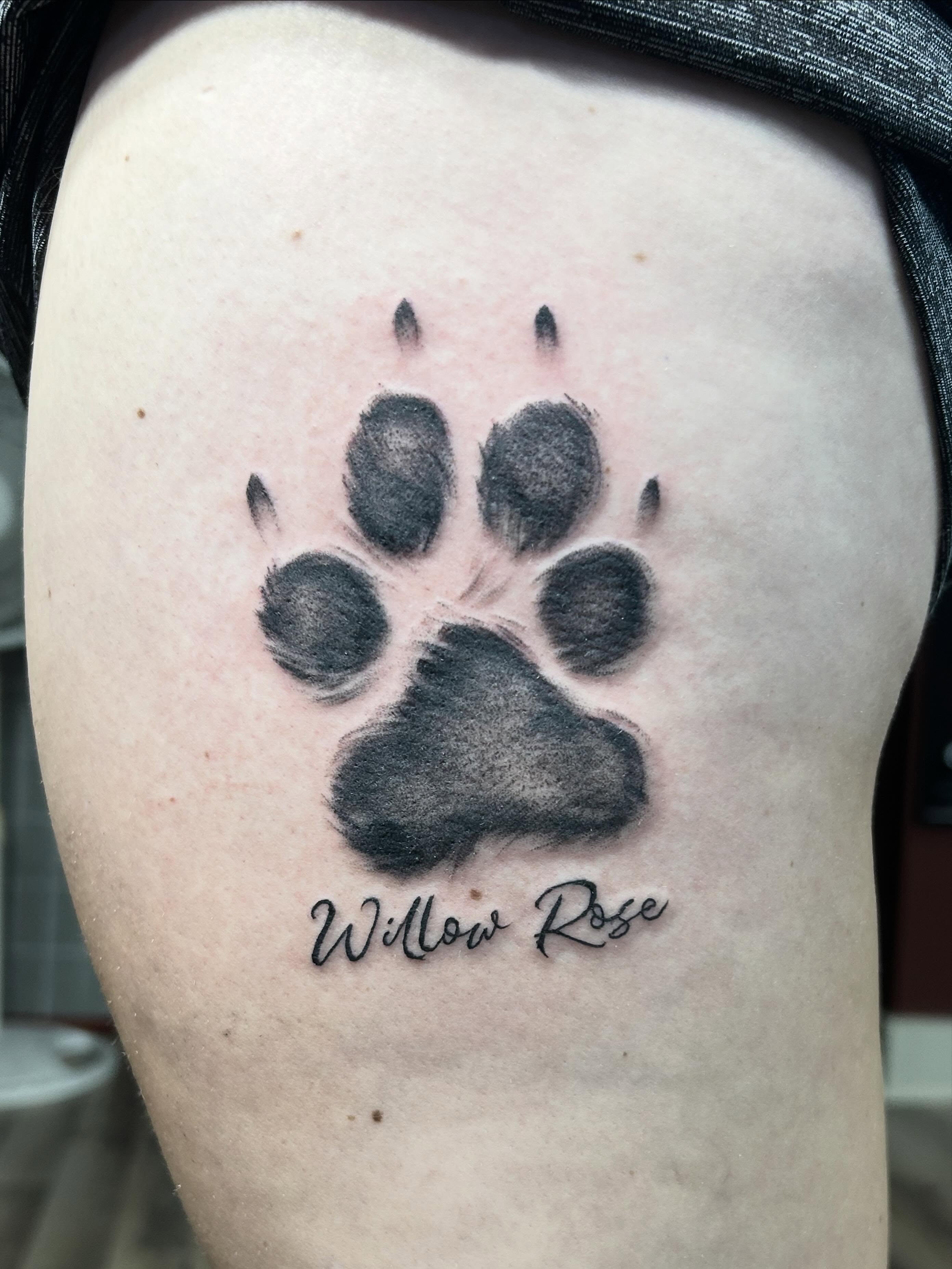 Paw print black and grey tattoo on the thigh by Dan Schuster
