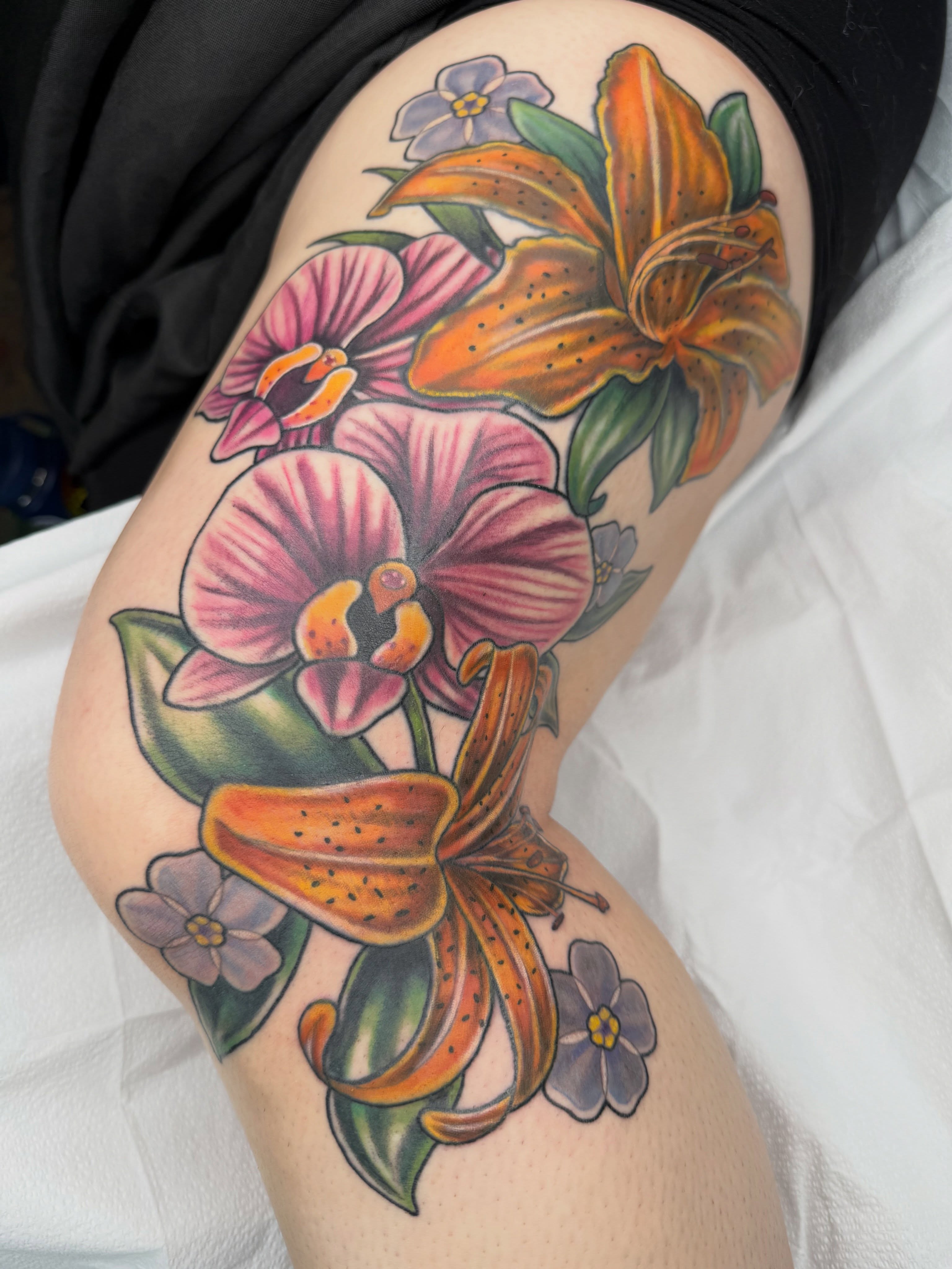 Floral bouquet realism tattoo on the thigh by AJ Jensen