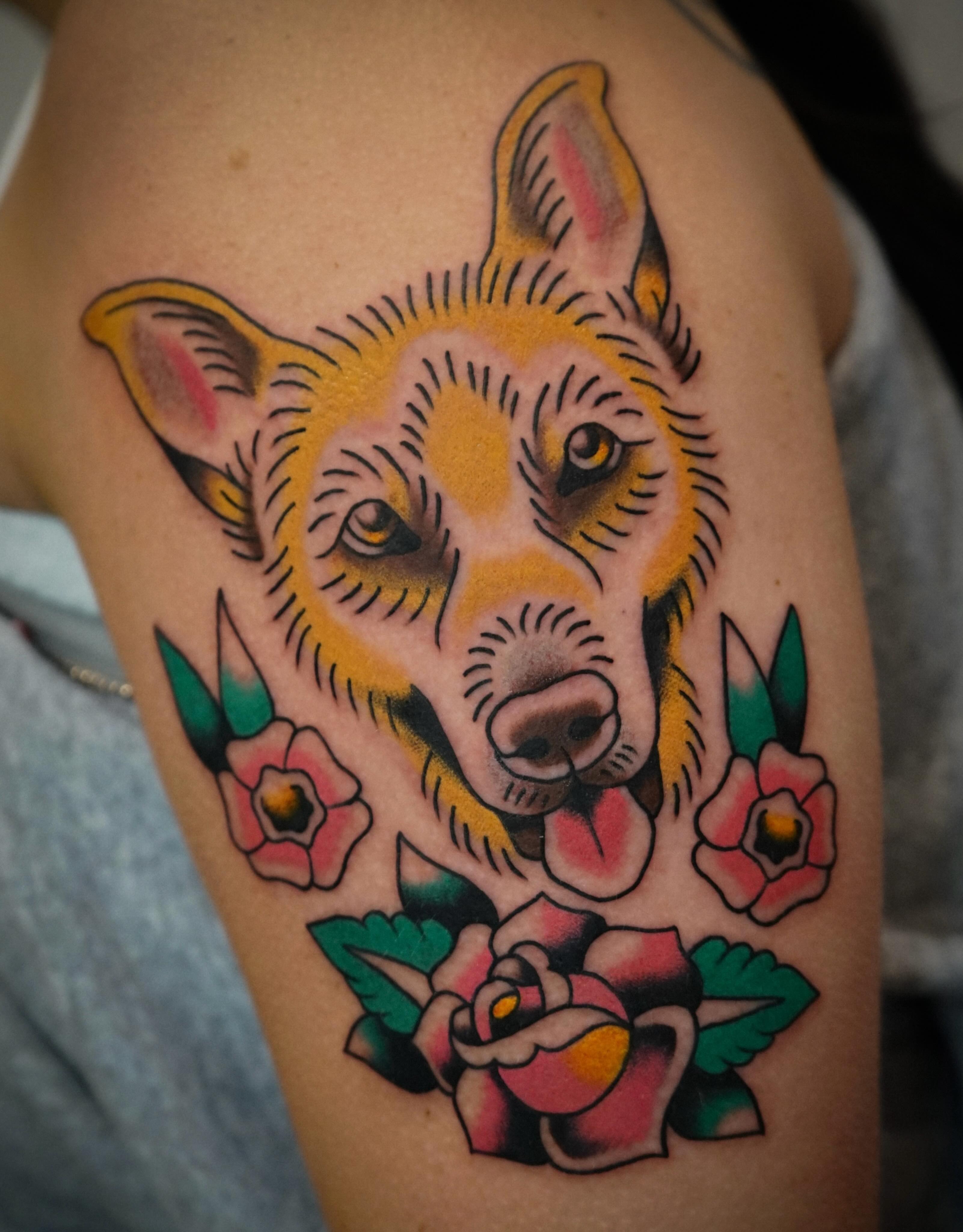 Dog with flowers American traditional tattoo on the upper arm by Emily Devenz