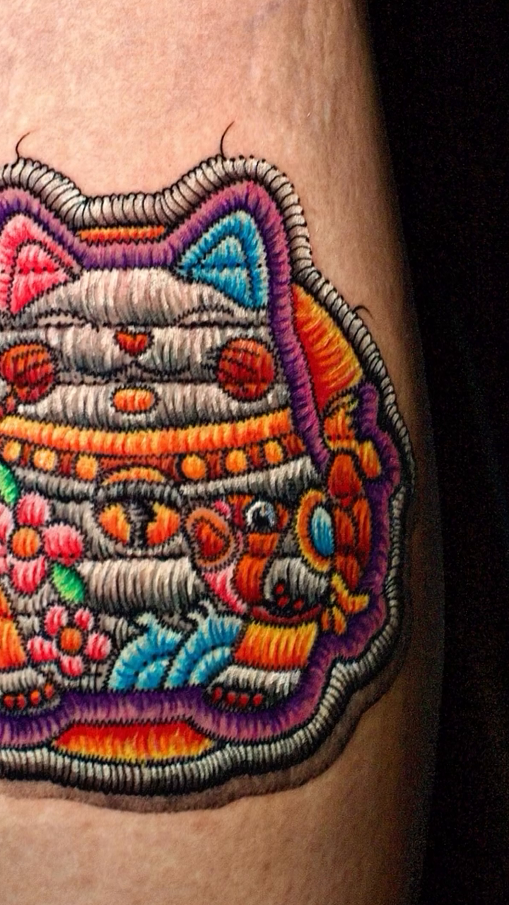 Embroidered cat with colorful details tattoo on the forearm by Yana Aizen