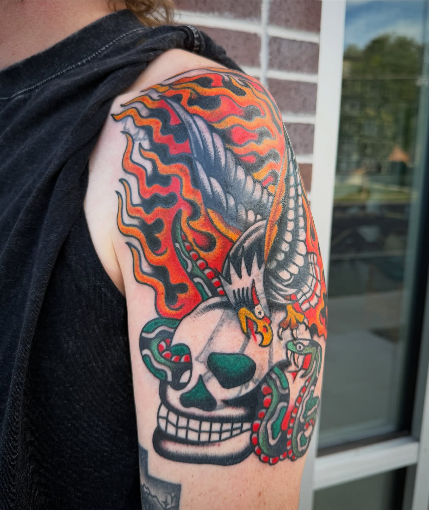 Skull with snakes American traditional tattoo on the shoulder by Nick Judkins Tattoo