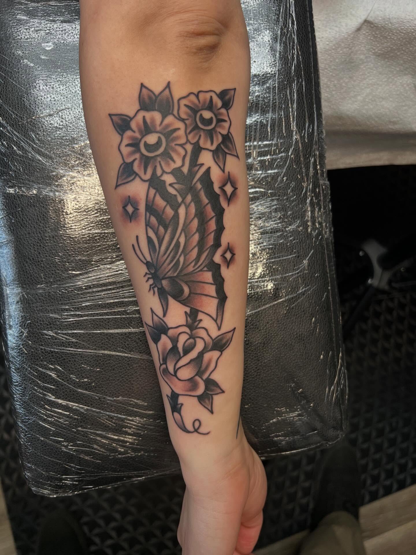 Butterfly and flowers American traditional tattoo on the forearm by Tyler Van Pelt