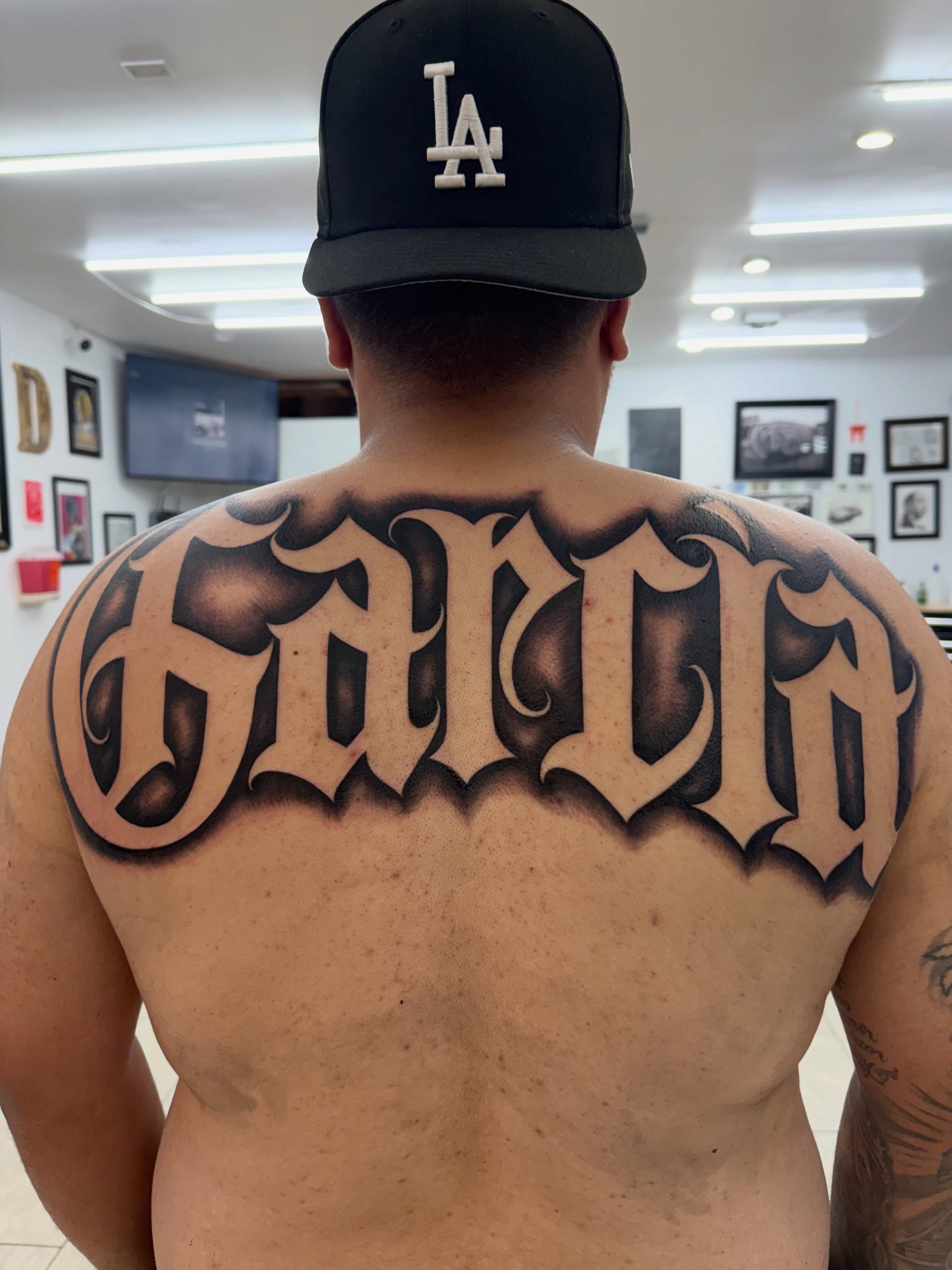 Garcia lettering script tattoo on the back by Daniel Lopez Tattoos