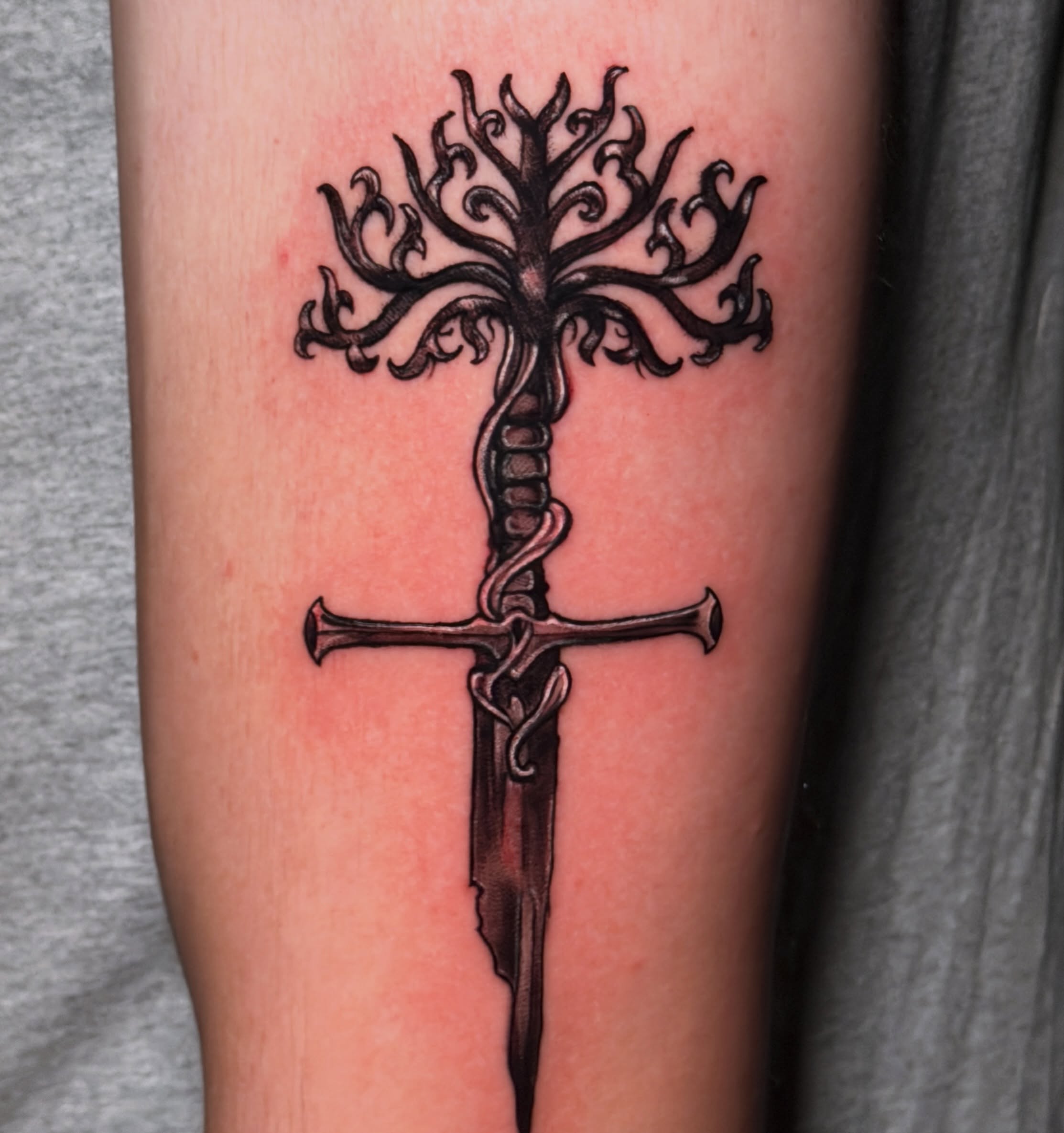 Sword and tree black and grey tattoo on the forearm by Breanna Fraielli