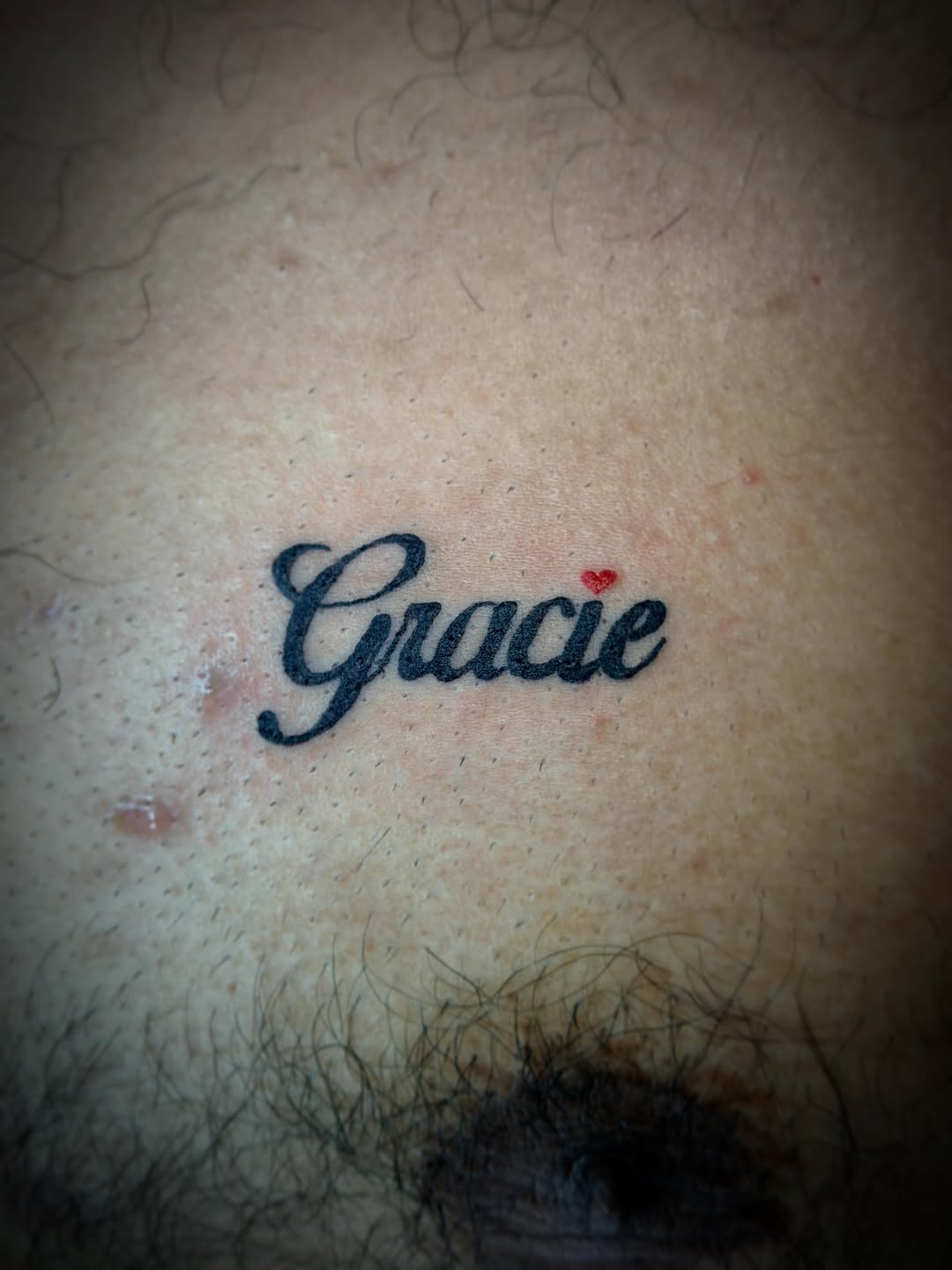 Name "Gracie" with a small heart lettering tattoo on the chest by Rylan Thorndyke - Tattoo Artist, Las Vegas, Nevada