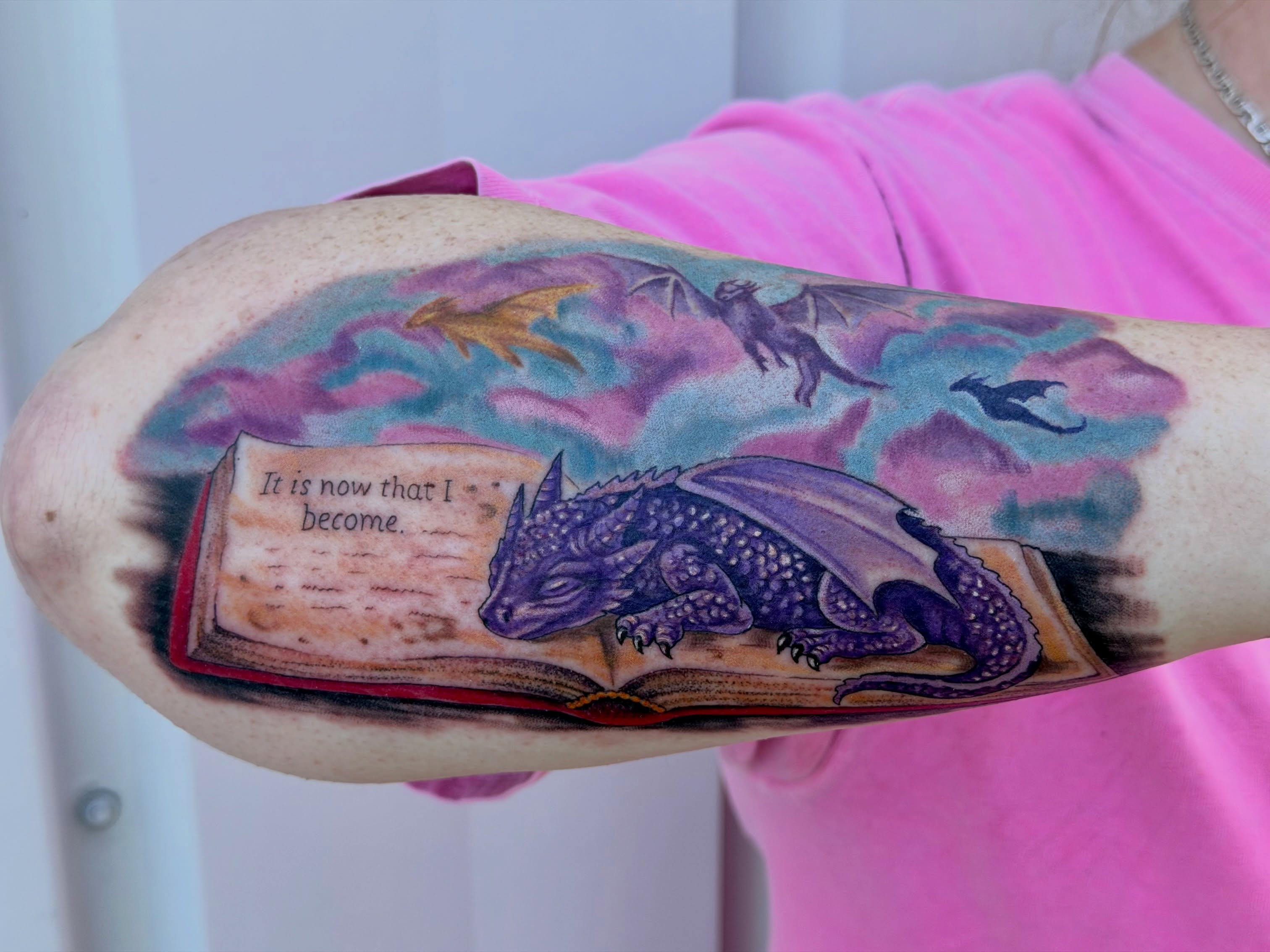 Dragon and book realism tattoo on the forearm by Caitlynn Austin