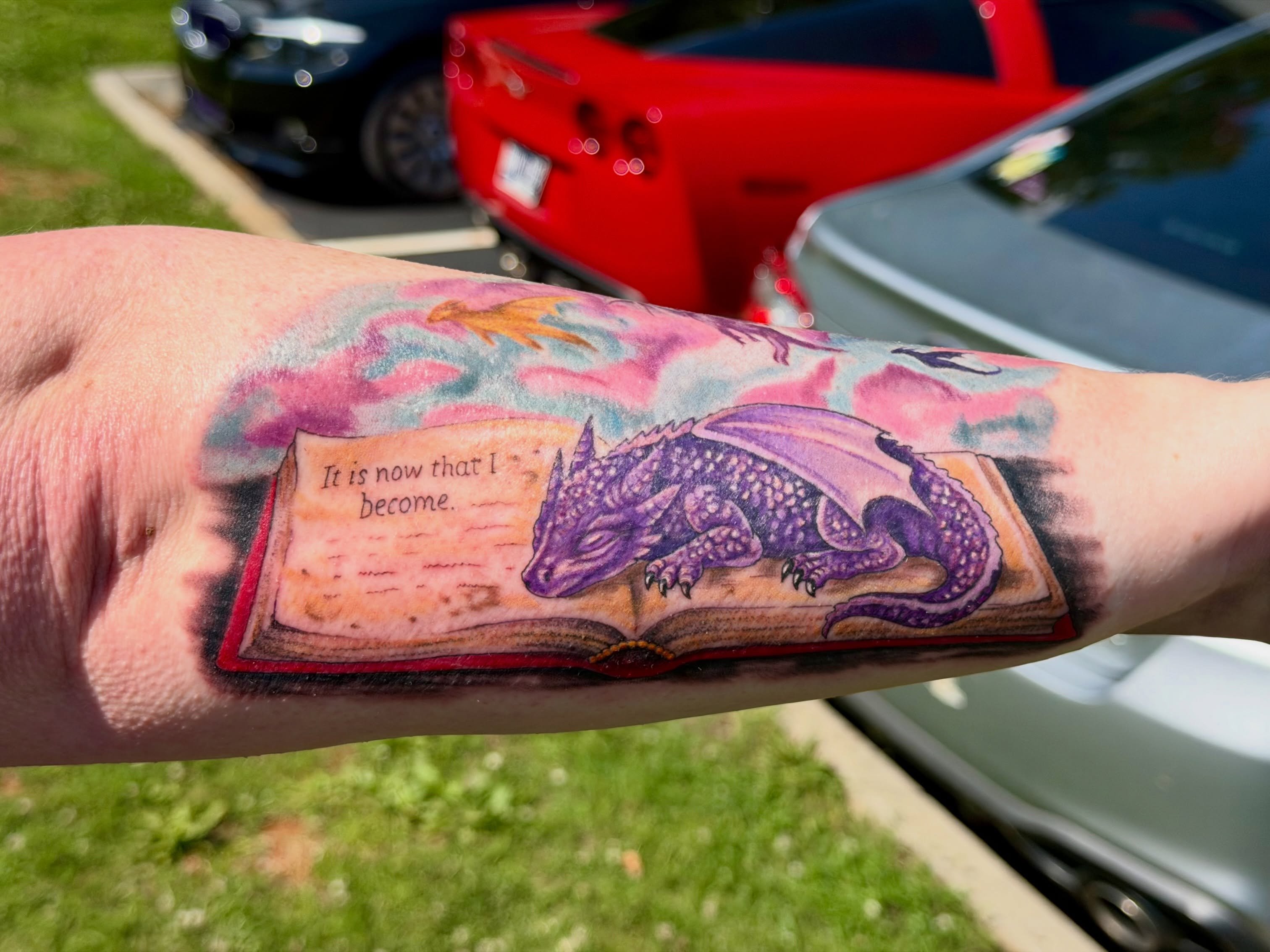Book with dragon realism tattoo on the forearm by Caitlynn Austin