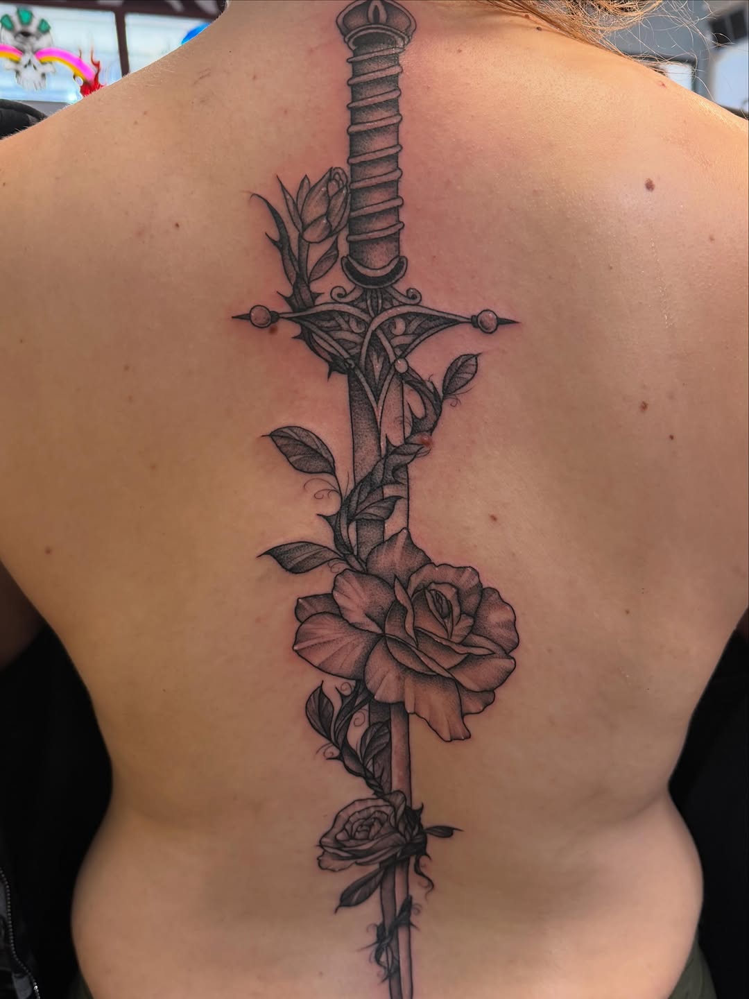 Sword and roses ornamental tattoo on the back by Madilynn Klassen