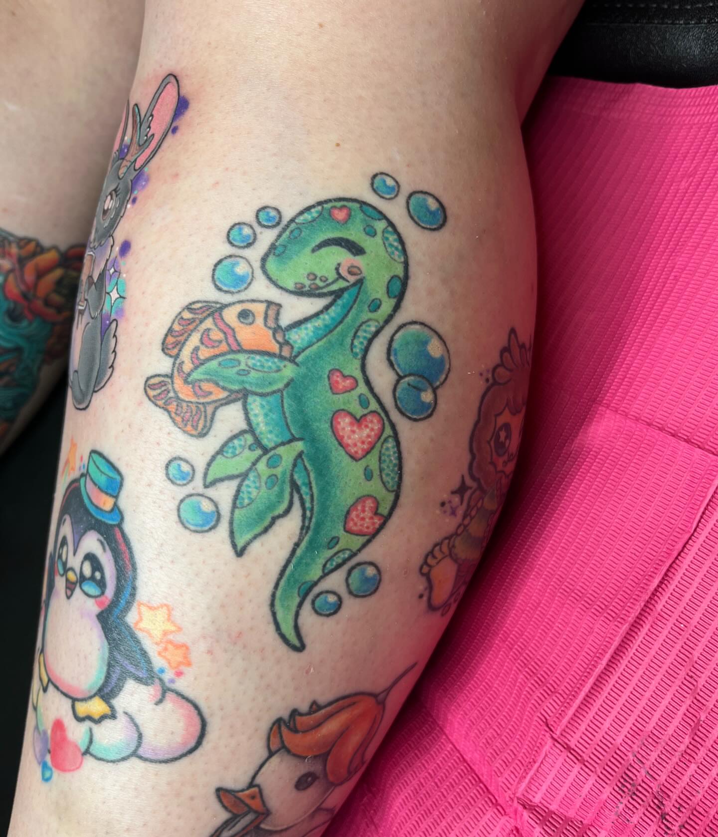 Dinosaur and fish new school tattoo on the upper arm by Ash Wheeler