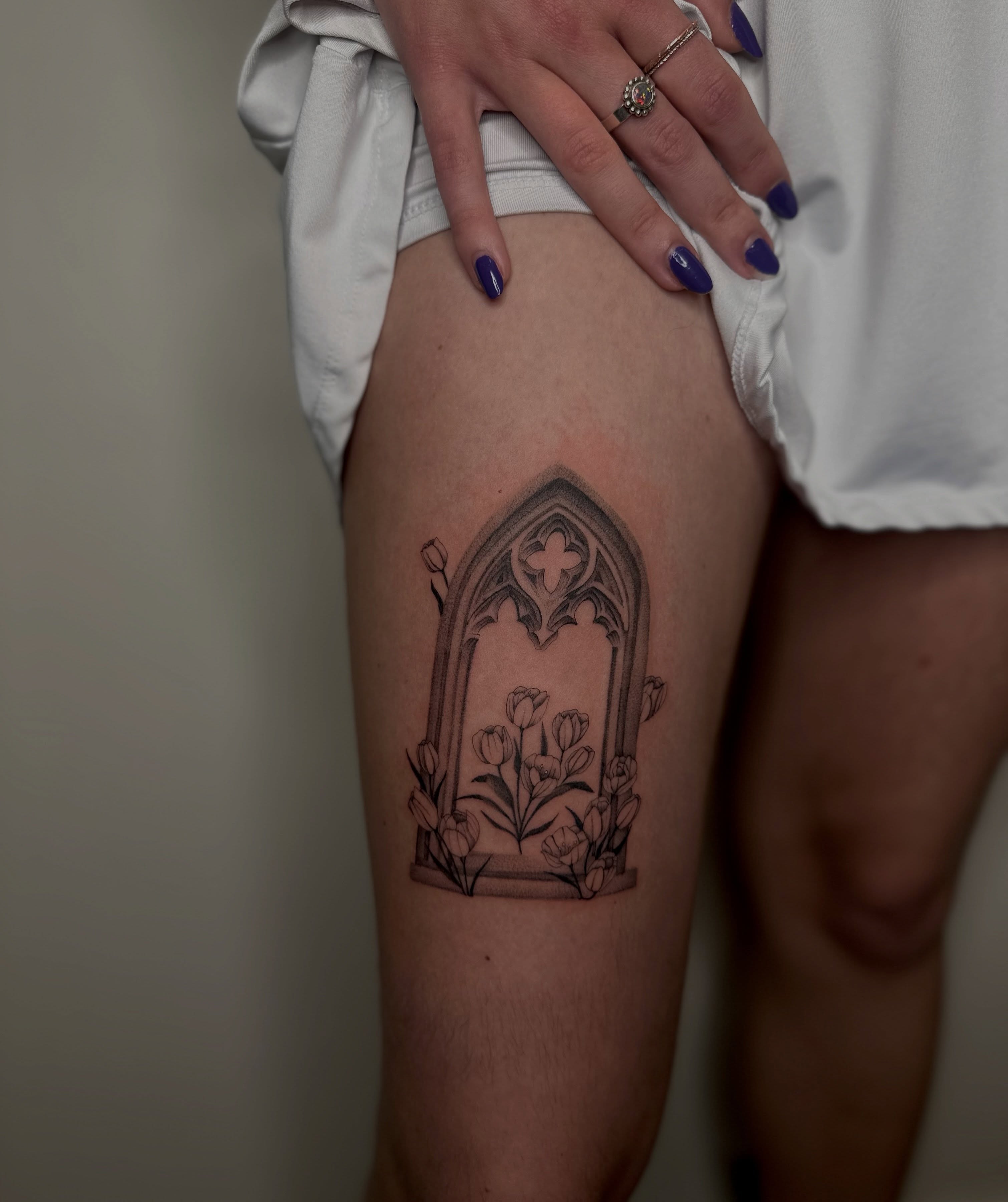 Gothic window with flowers black and grey tattoo on the thigh by Macy Rae