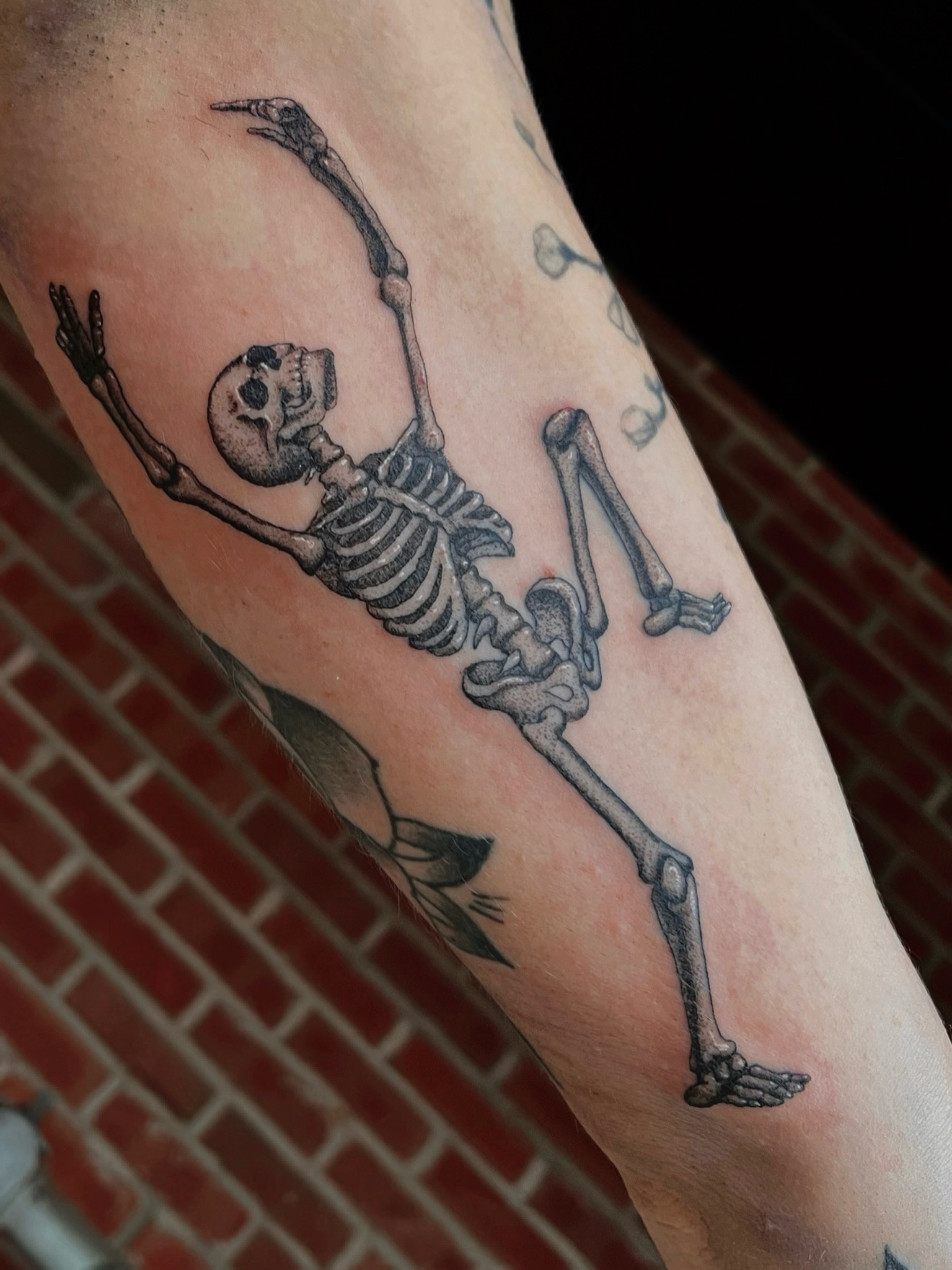 Skeleton diving black and grey tattoo on the forearm by Jackson Kirchhoff