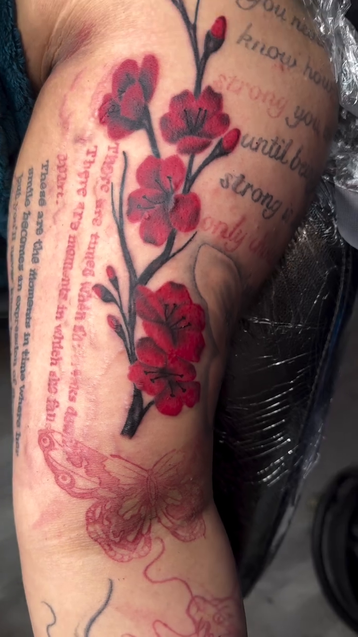 Cherry blossoms with script watercolor tattoo on the upper arm by Left My Mark