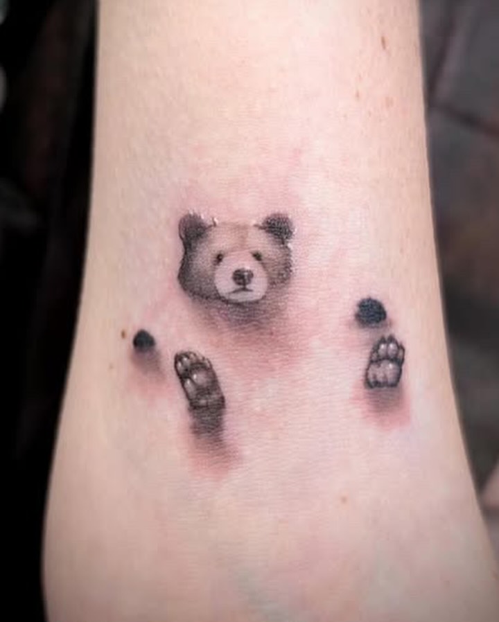 Bear peeking out realism tattoo on the forearm by Rhiannon