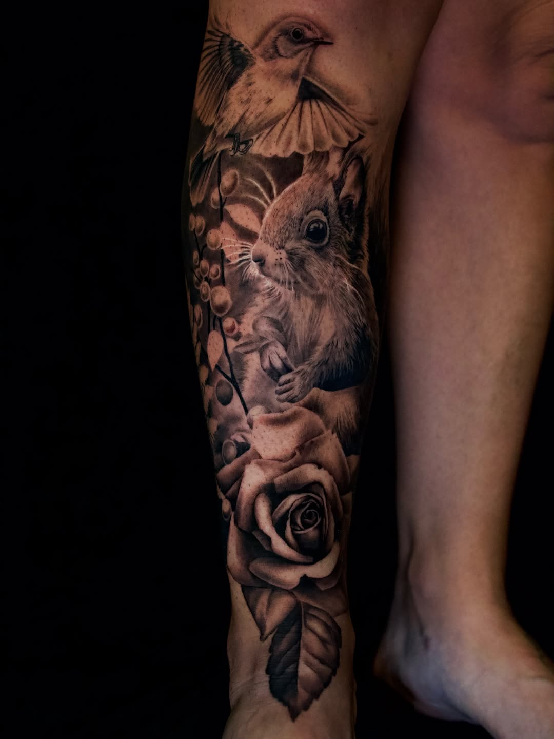 Squirrel, bird, and rose surrealism tattoo on the forearm by April Lynn