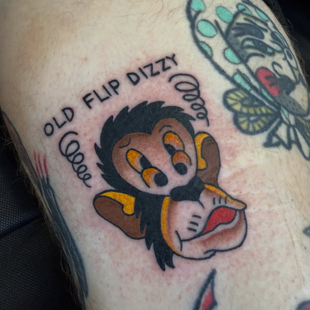 Cartoon monkey with text new school tattoo on the thigh by Nick Tumminello