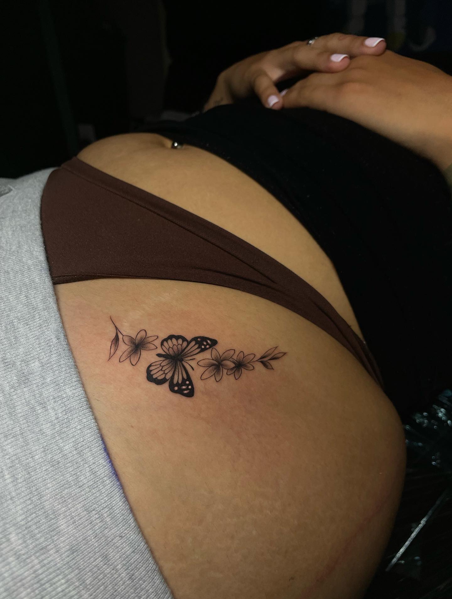 Butterfly and flowers black and grey tattoo on the thigh by Nikko