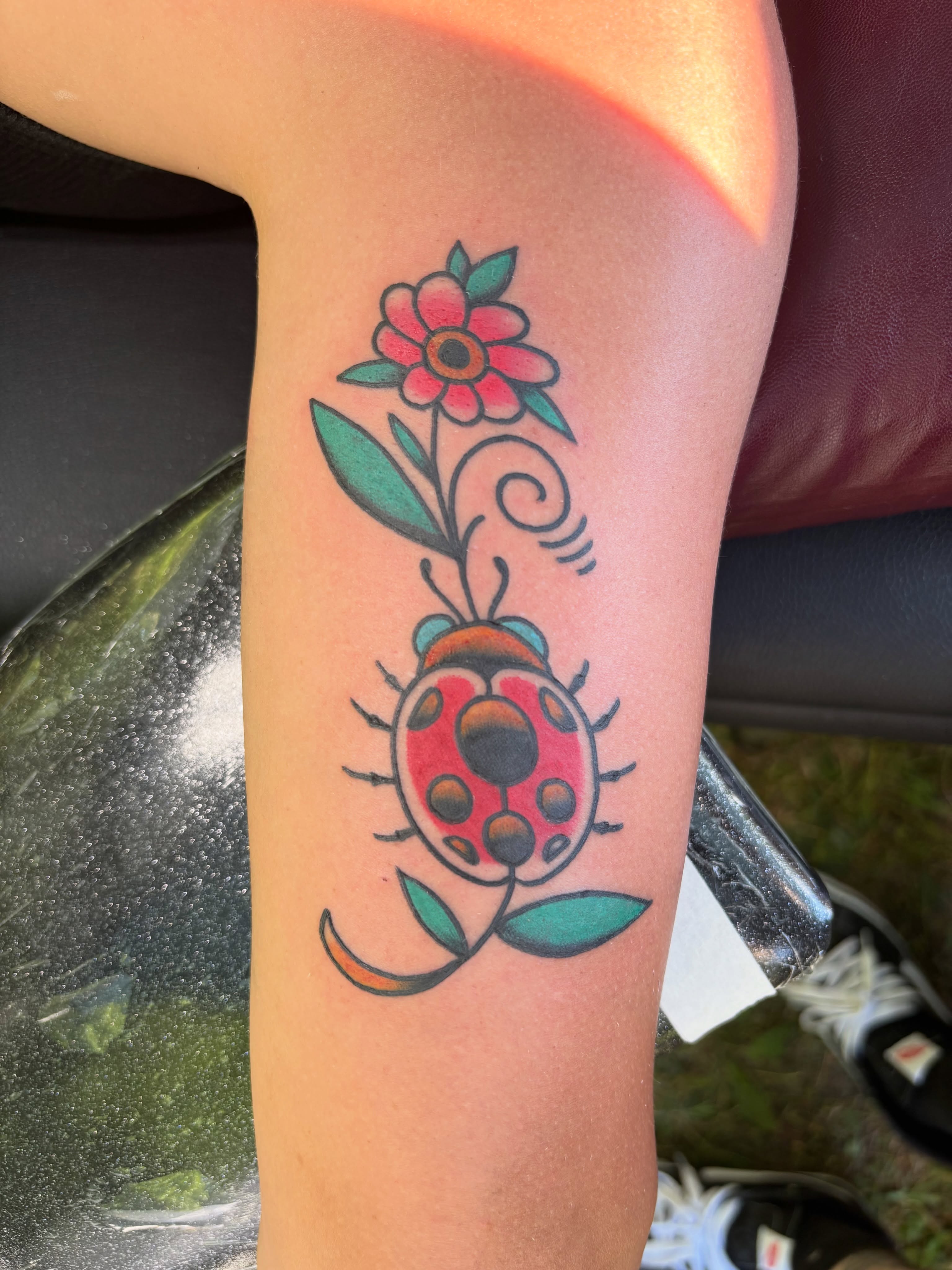 Ladybug and flower American traditional tattoo on the forearm by @koma_tk