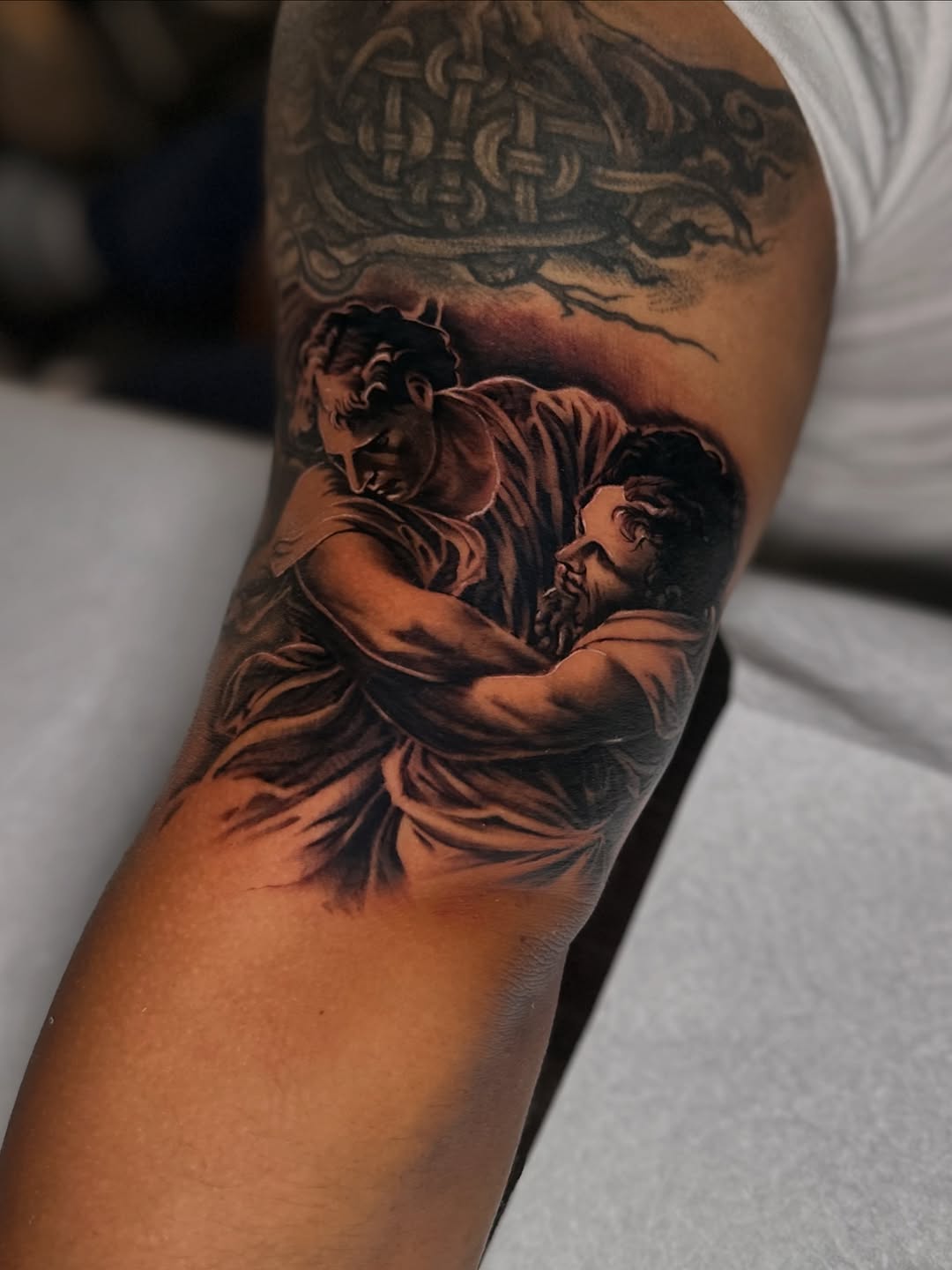 Two figures wrestling realism tattoo on the forearm by Mando