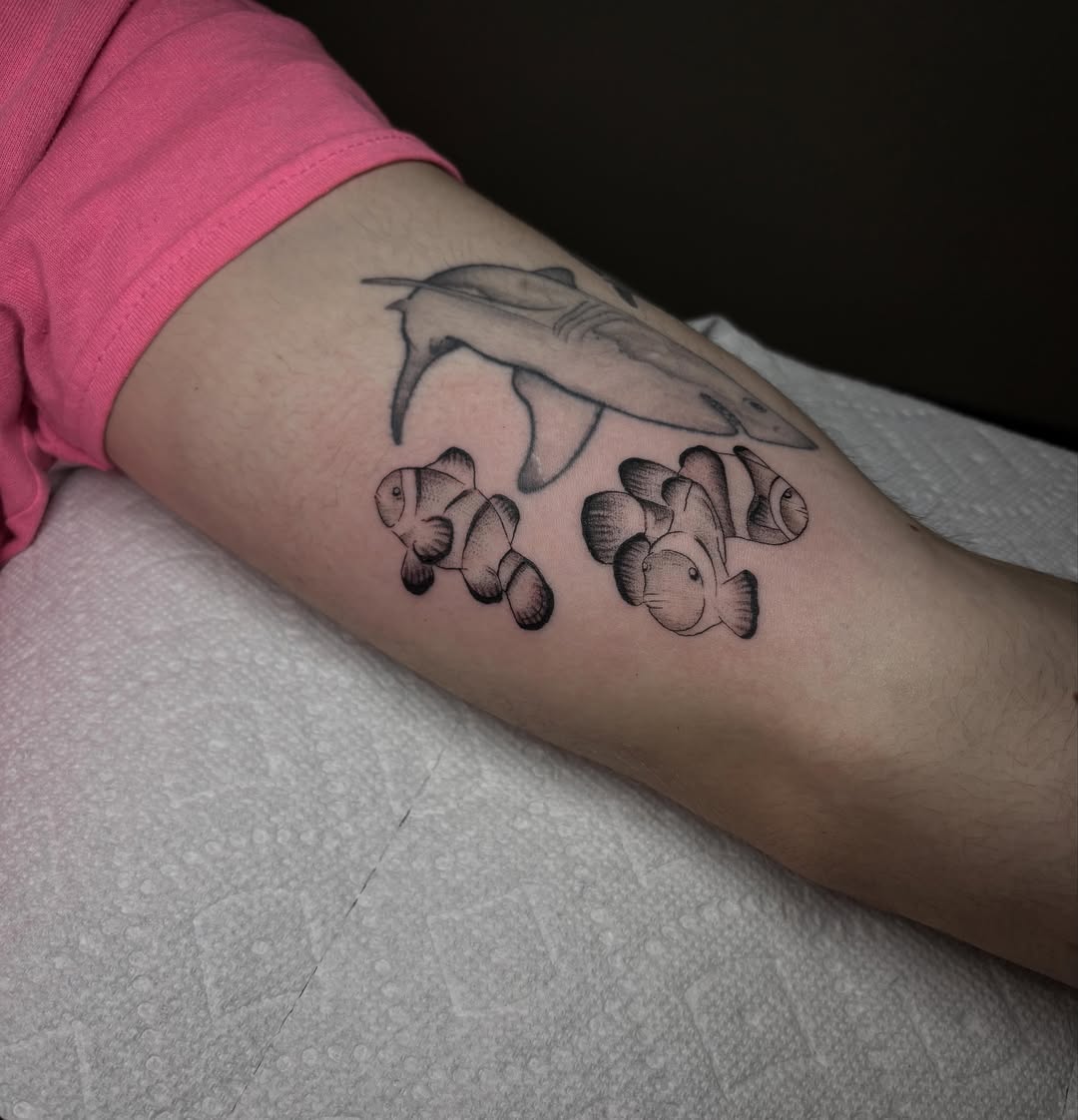 Clownfish and shark black and grey tattoo on the forearm by Grace L