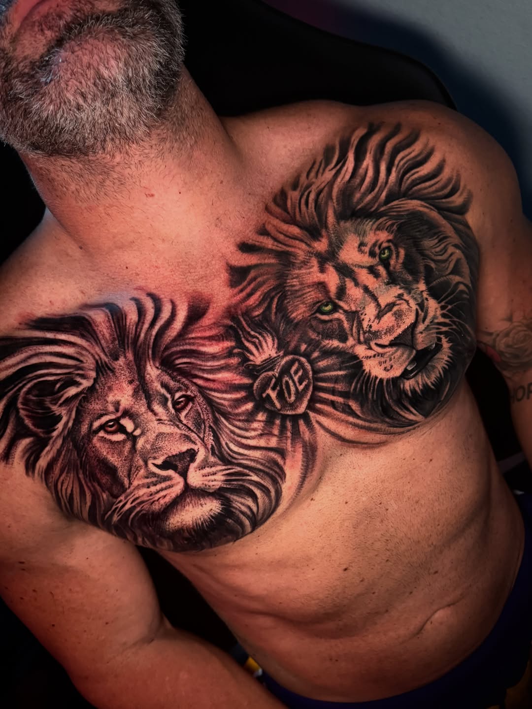 Two lions and heart with initials realism tattoo on the chest by Henry Fuentes