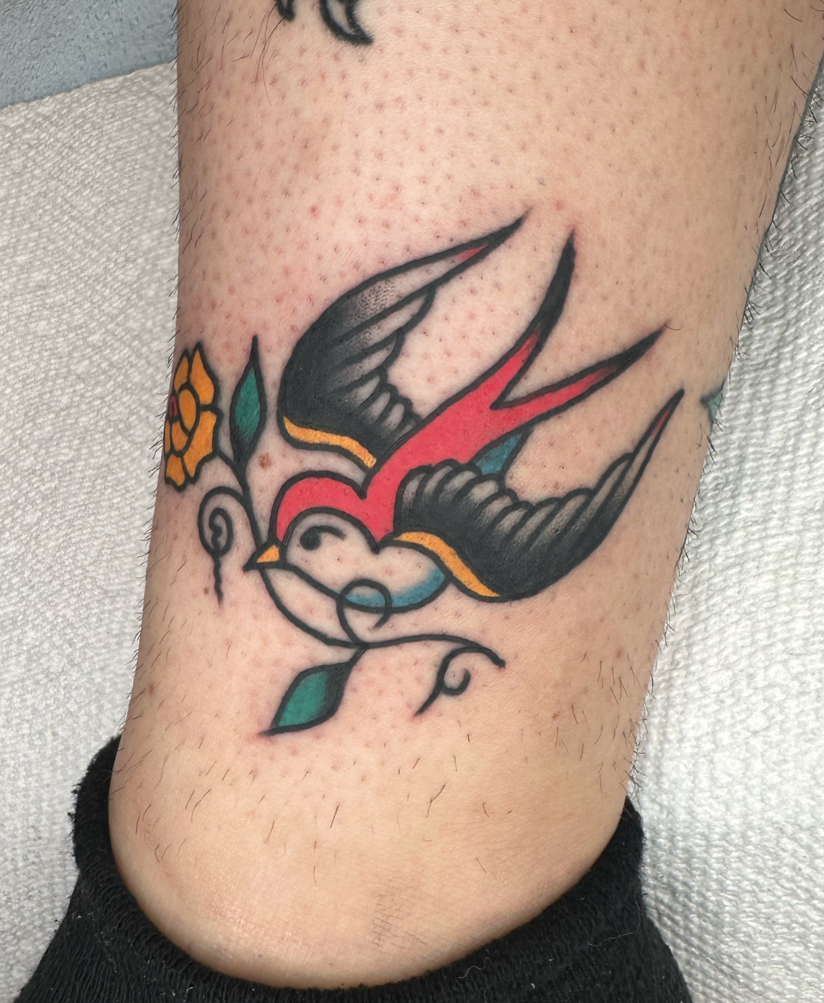 Swallow and flower American traditional tattoo on the forearm by Brock Johnson