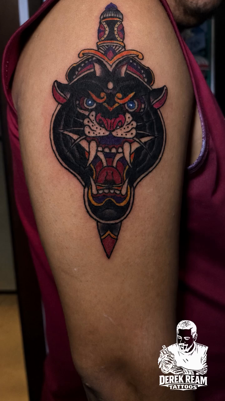 Panther head with dagger realism tattoo on the shoulder by Derek Ream