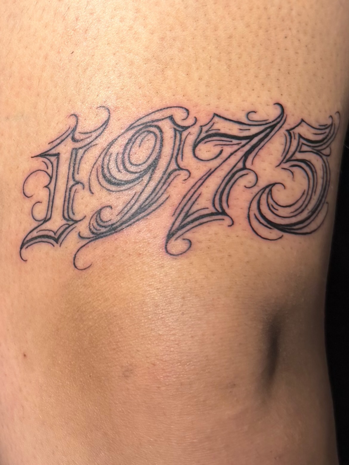 1975 lettering script tattoo on the ribs by Star Tattoos ⚜️