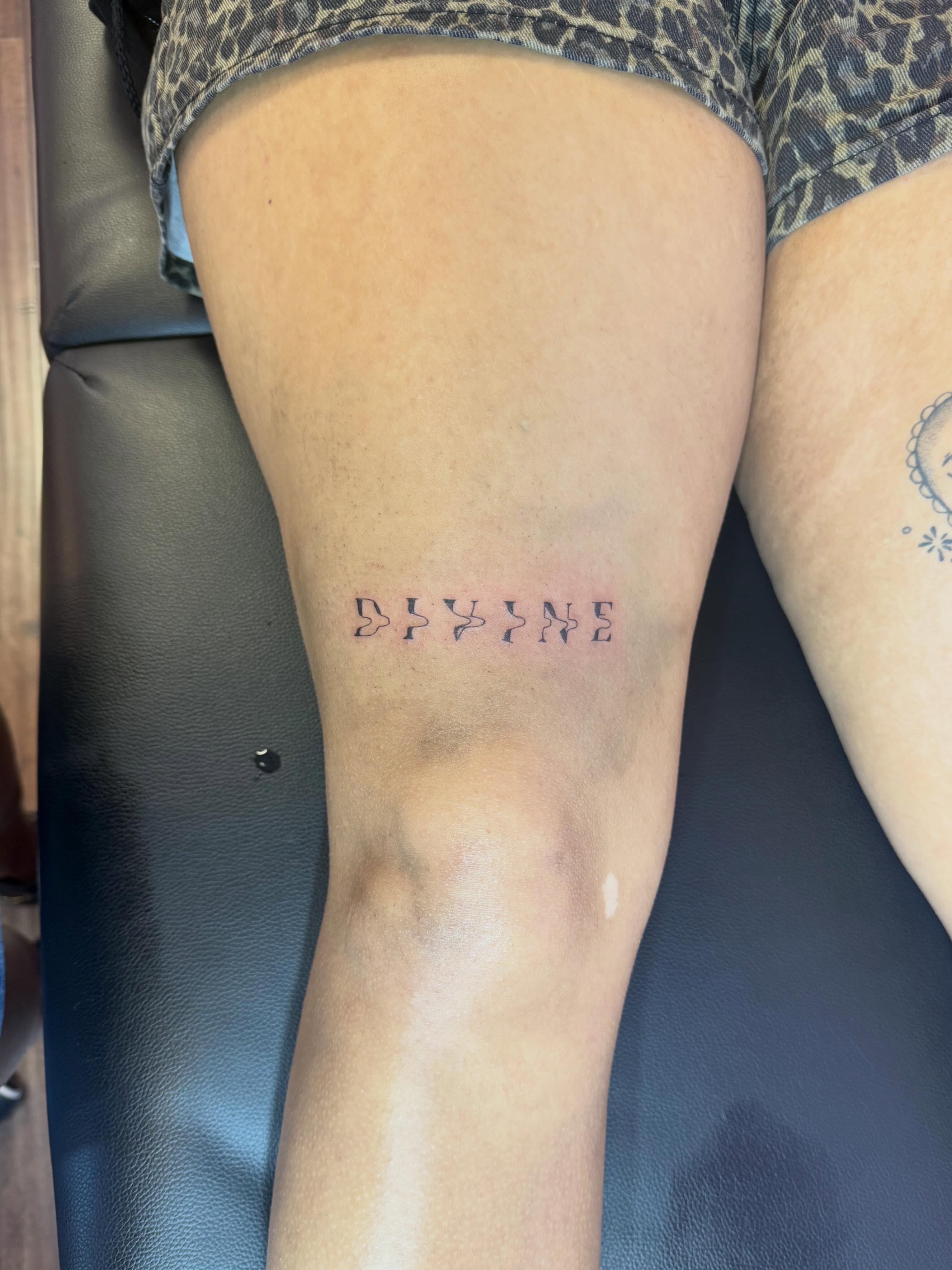 DIVINE lettering tattoo on the leg by Jay