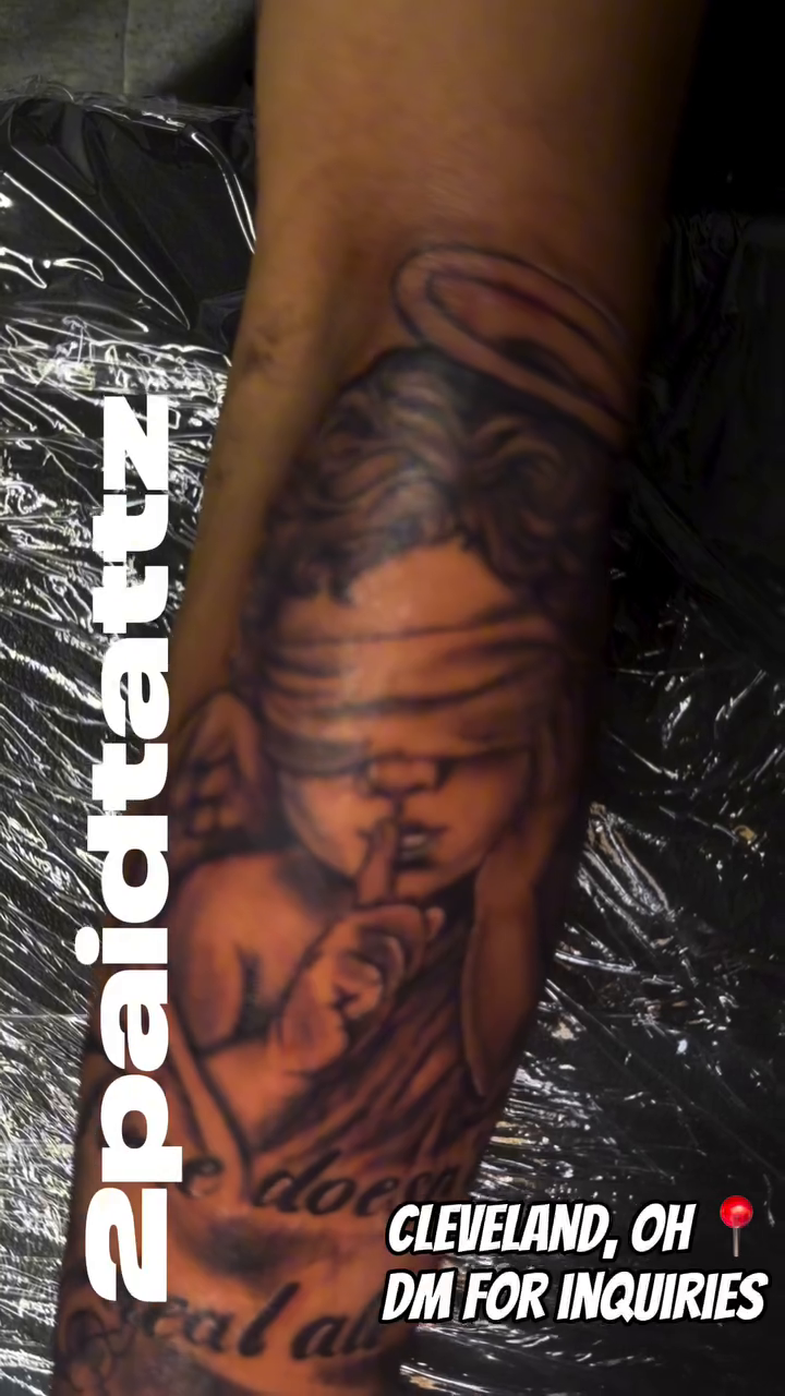 Blindfolded angel with text realism tattoo on the forearm by 2PaidTattz