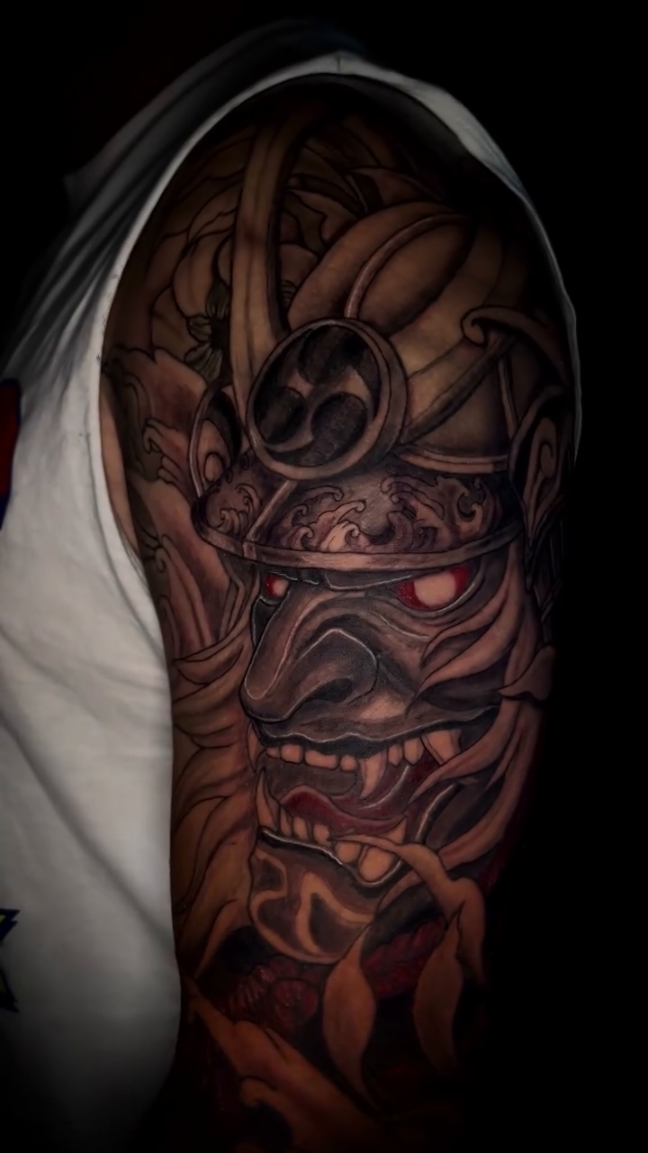 Samurai mask and floral elements Japanese tattoo on the upper arm by bev