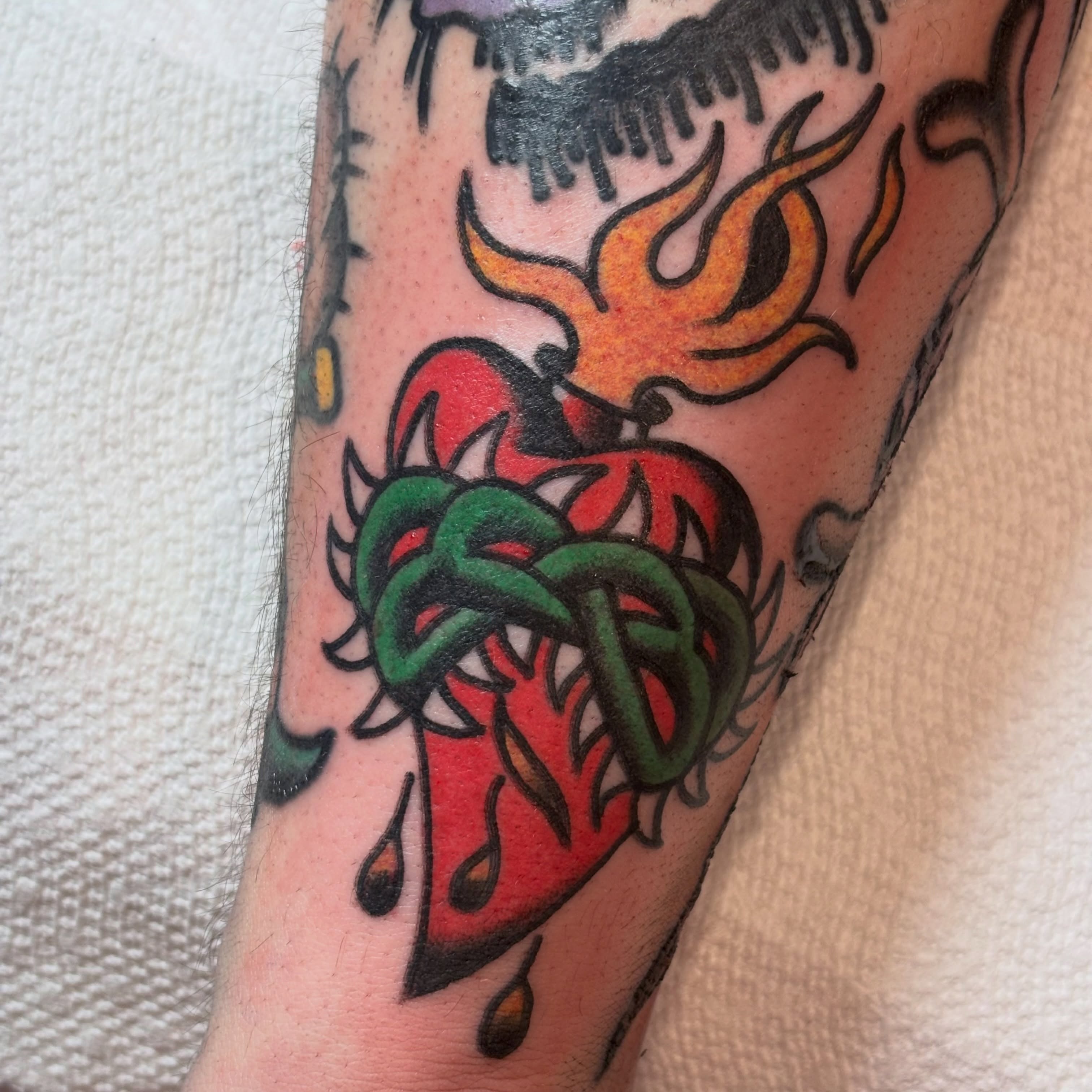 Heart with flames American traditional tattoo on the forearm by Malachi