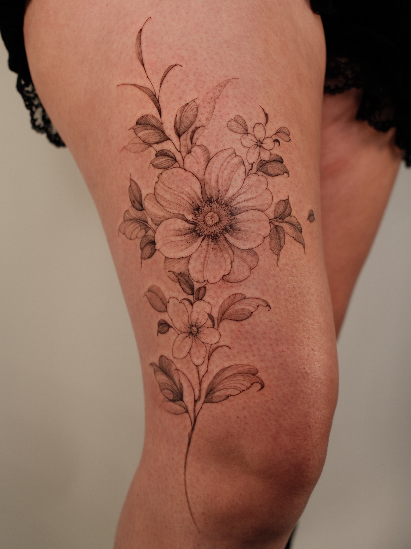 Flower bouquet black and grey tattoo on the thigh by LORIE π€ Floral Tattoo Artist, Los Angeles, California