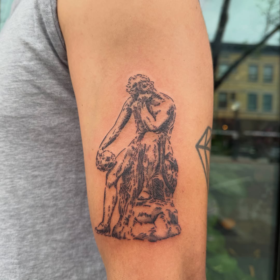 Statue of woman carrying child black and grey tattoo on the forearm by Kieara West