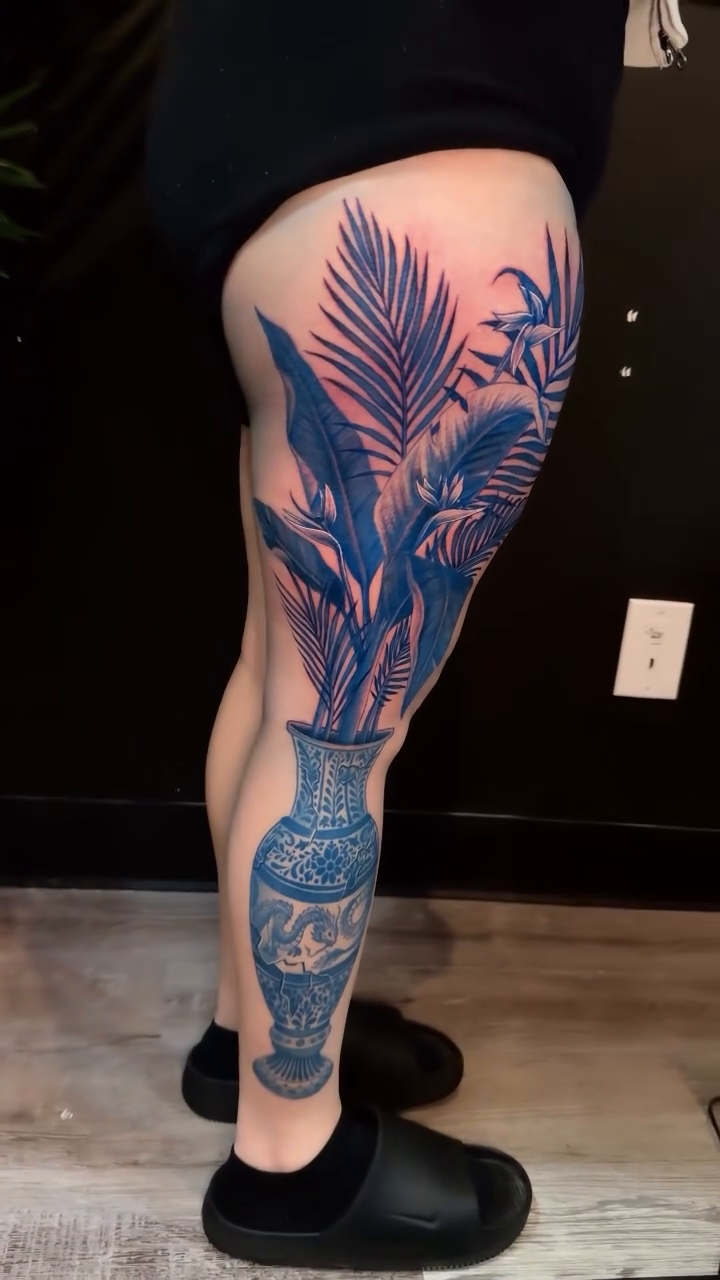Vase with tropical leaves surrealism tattoo on the leg by Christian