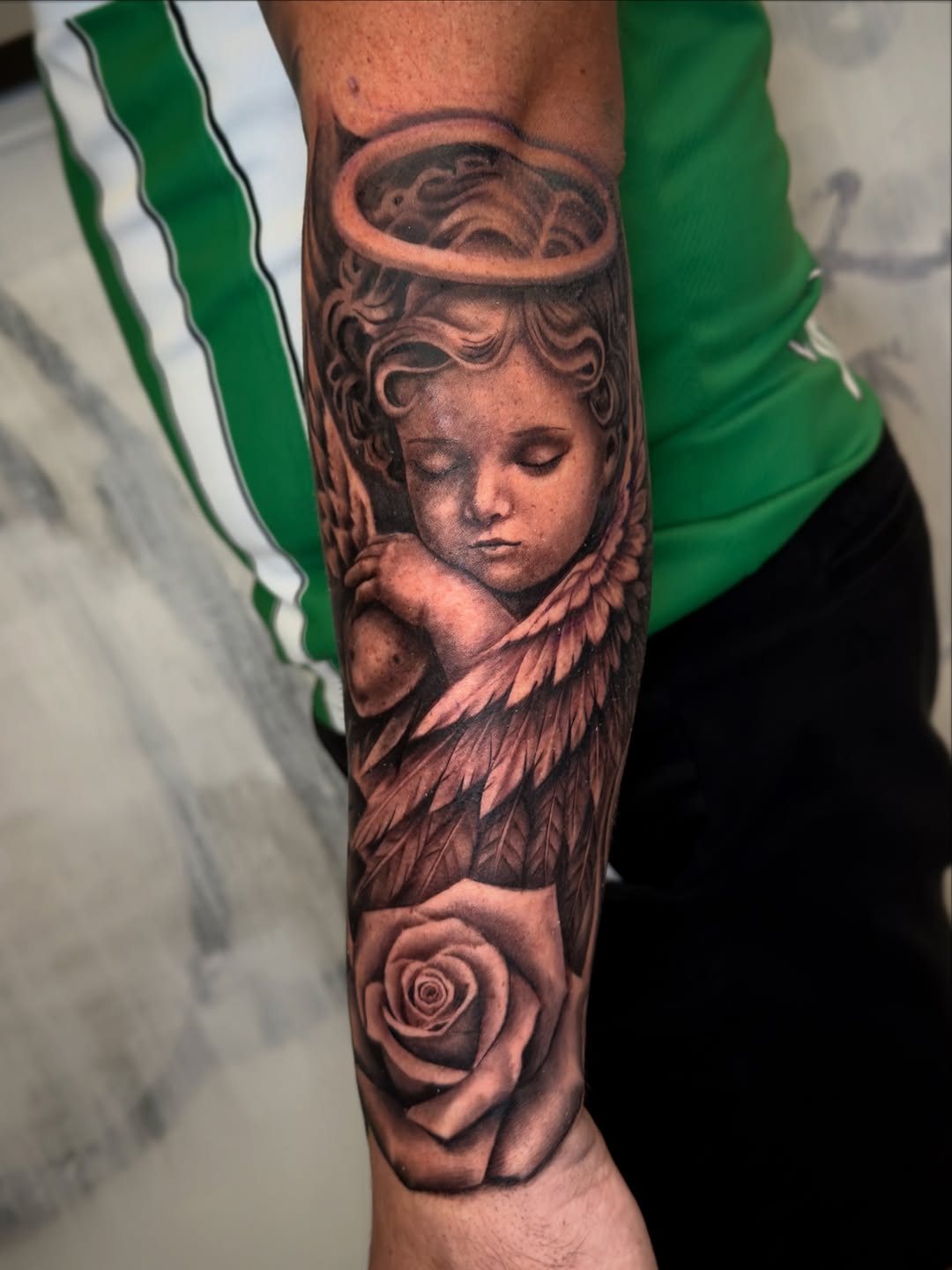 Cherub and rose realism tattoo on the forearm by Brandon Patino