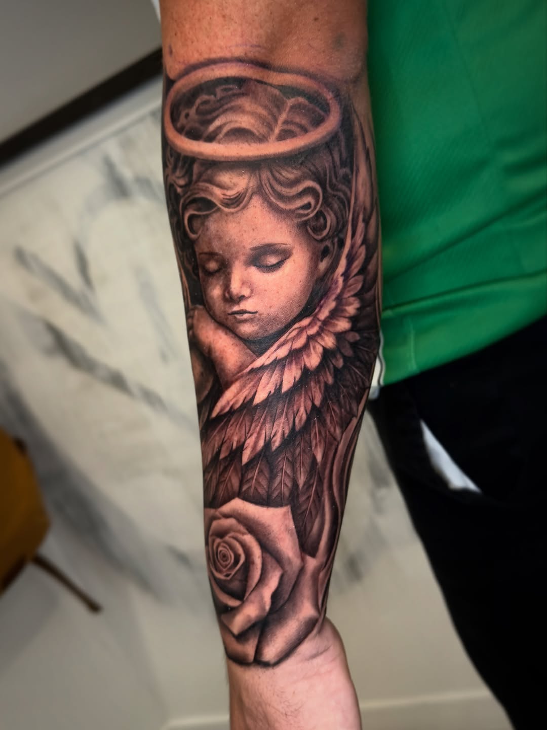 Cherub and rose realism tattoo on the forearm by Brandon Patino