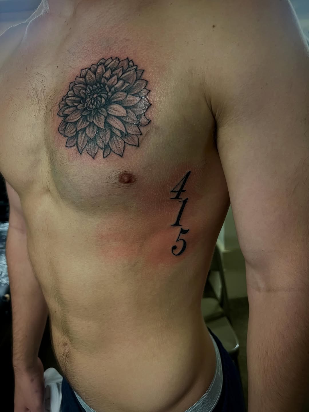 Dahlia flower and numbers geometric tattoo on the chest by Jelani