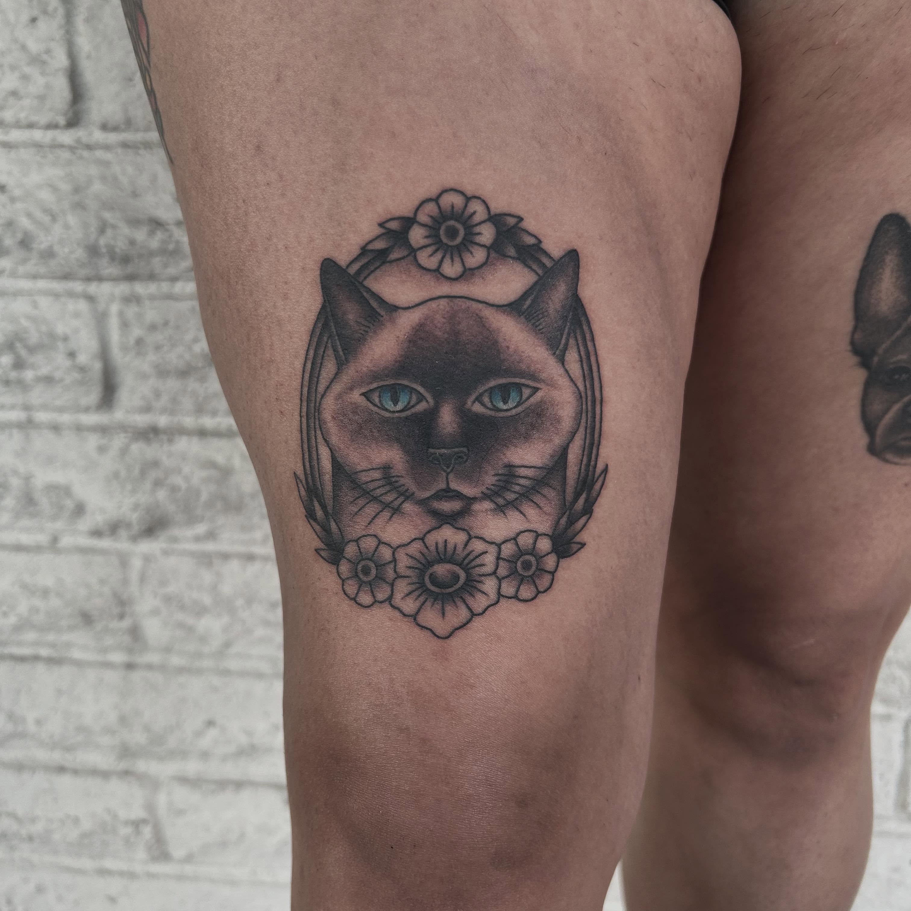 Cat with floral wreath realism tattoo on the thigh by Stephen Sanchez