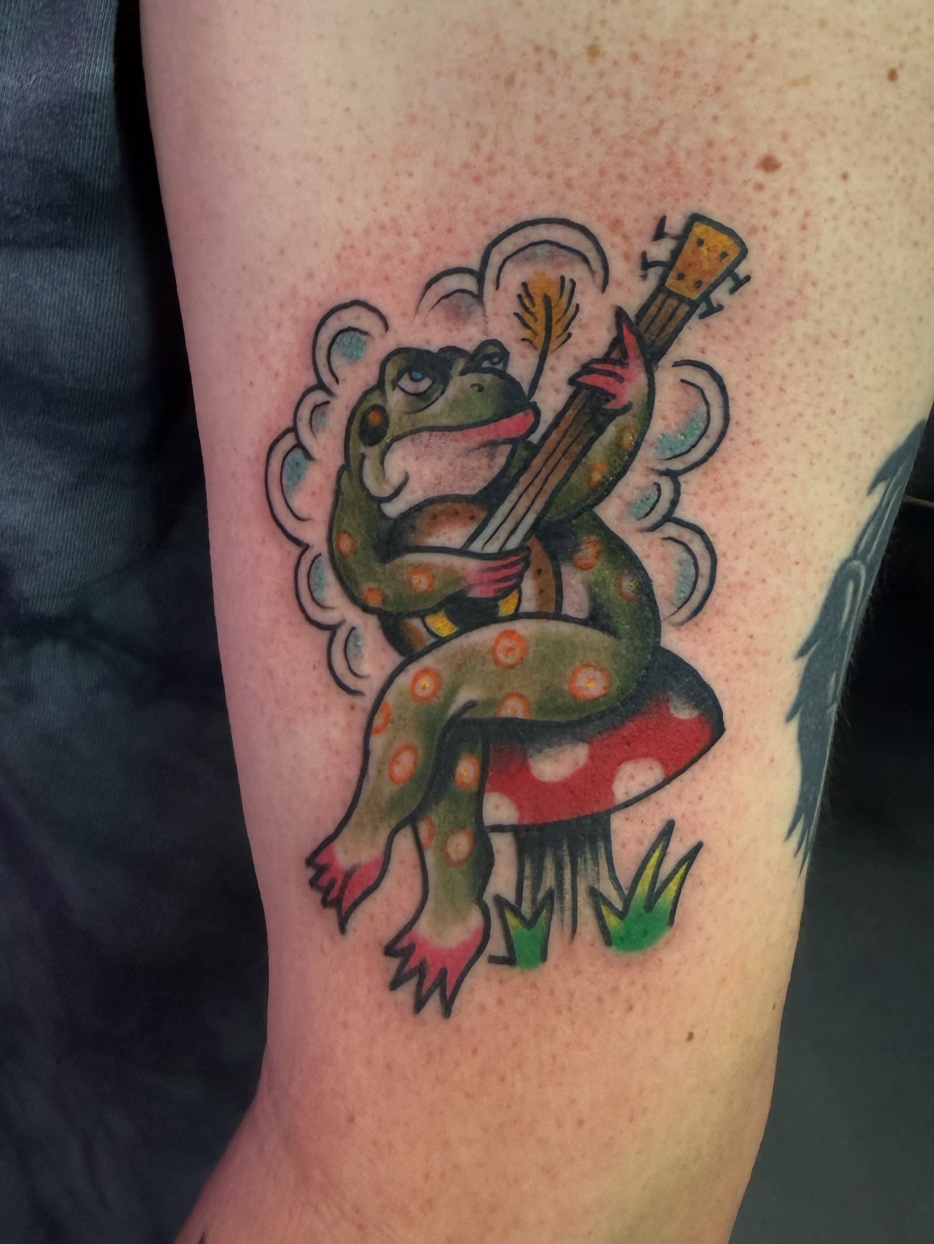 Frog playing guitar American traditional tattoo on the forearm by Shane Bonham