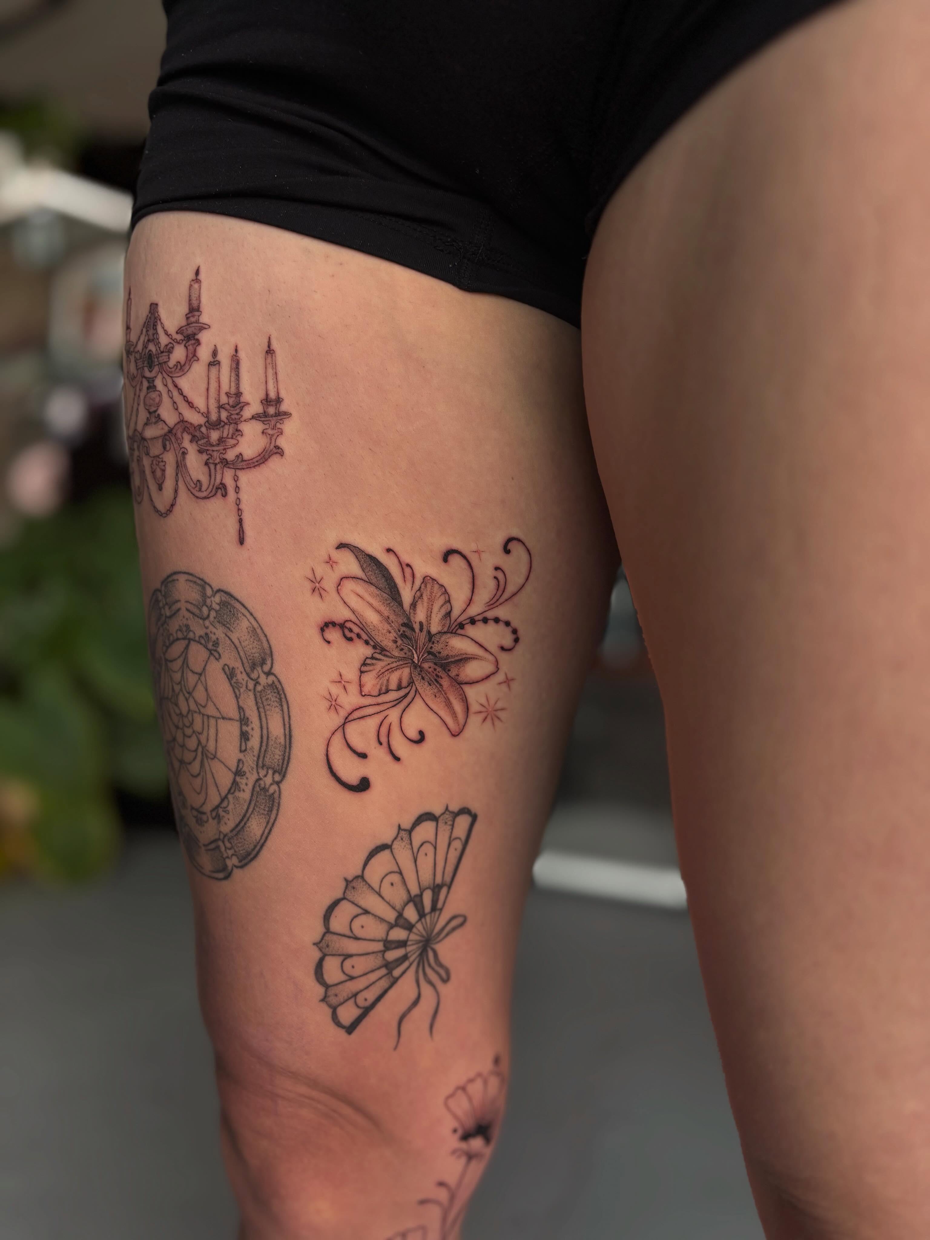 Chandelier, lily, butterfly black and grey tattoo on the thigh by Marissa Whitaker