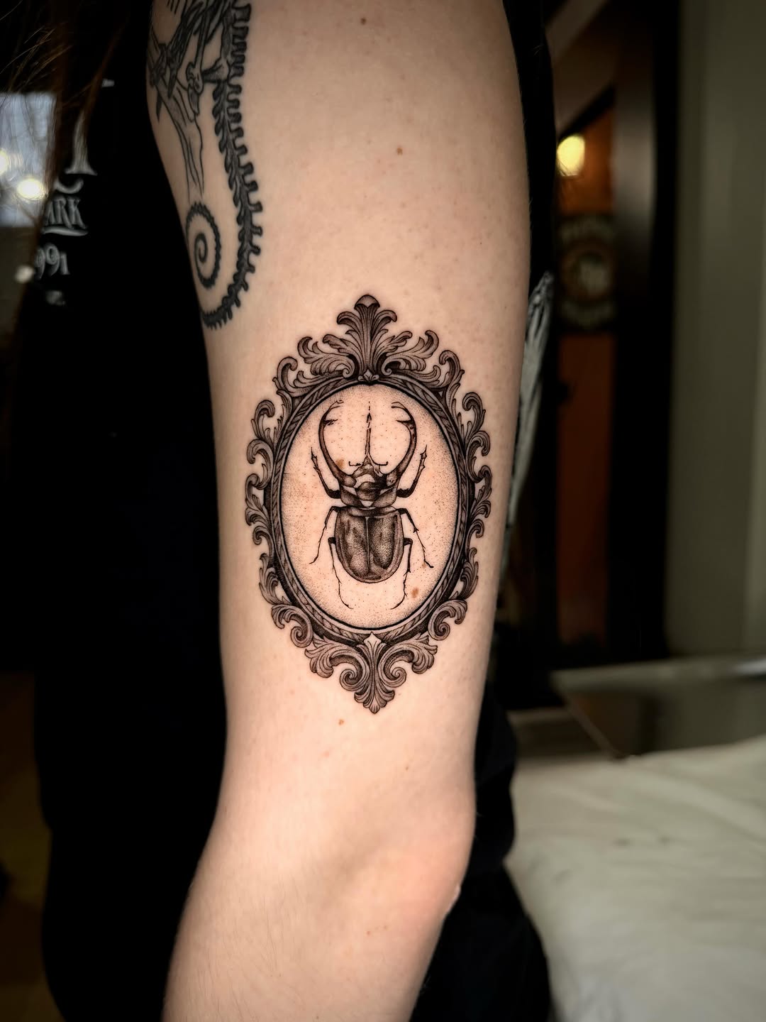 Beetle in ornate frame tattoo on the forearm by Ingrid Rojas