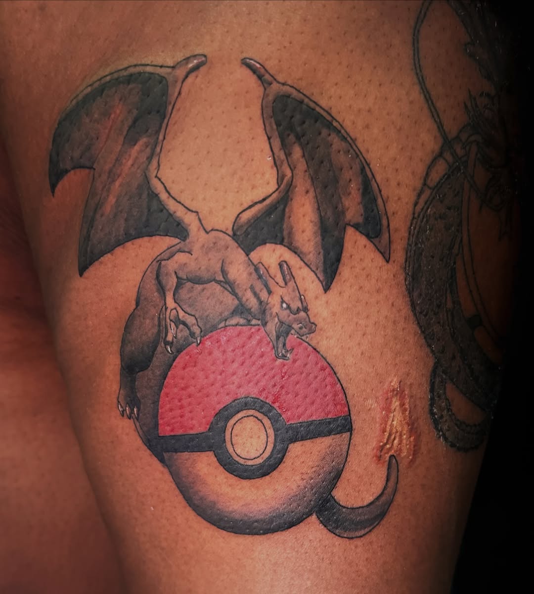 Charizard on a pokeball new school tattoo on the thigh by Alexander Haber