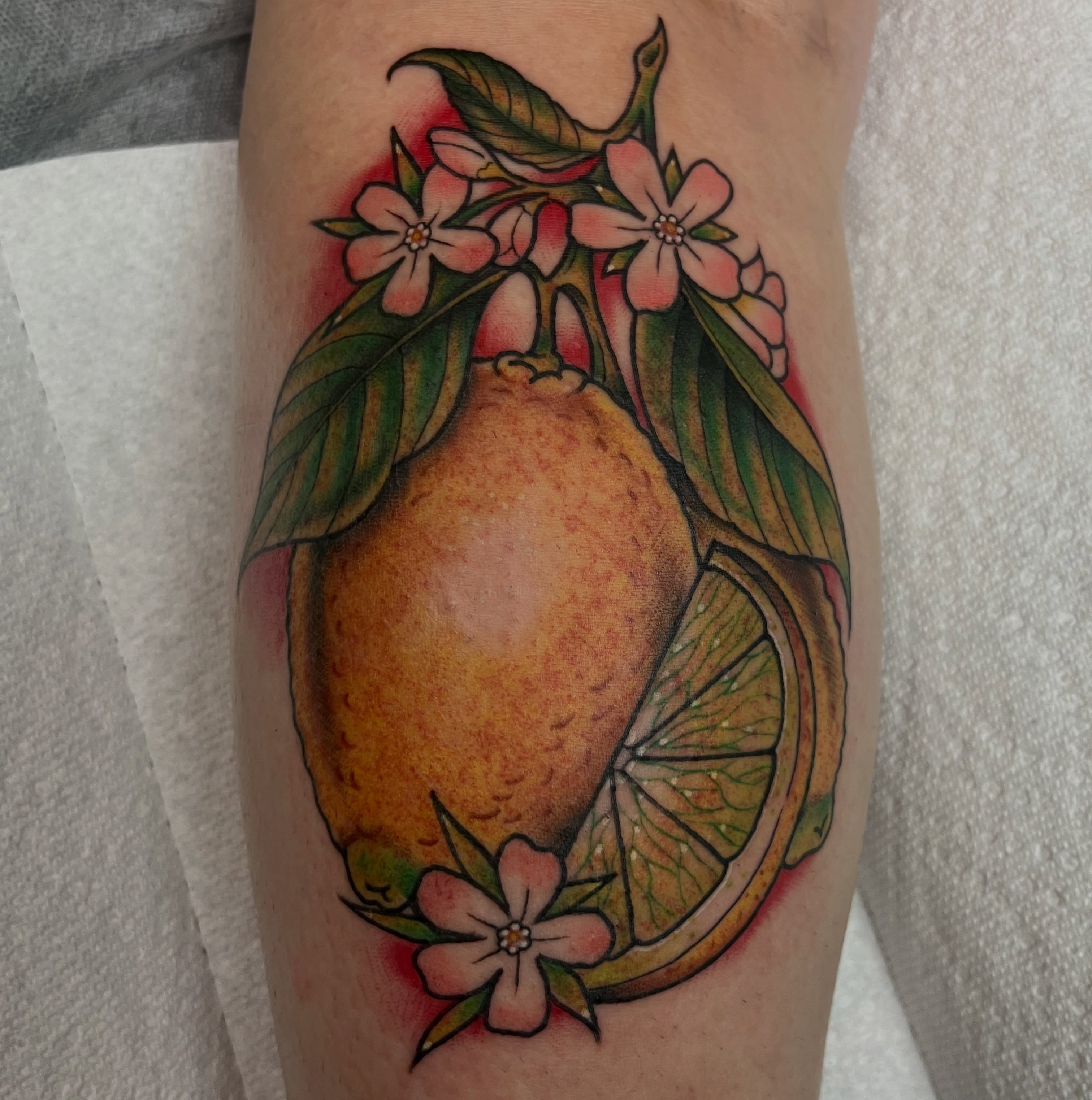 Lemon and flowers realism tattoo on the forearm by Tattoos and art by Ghost Shipe