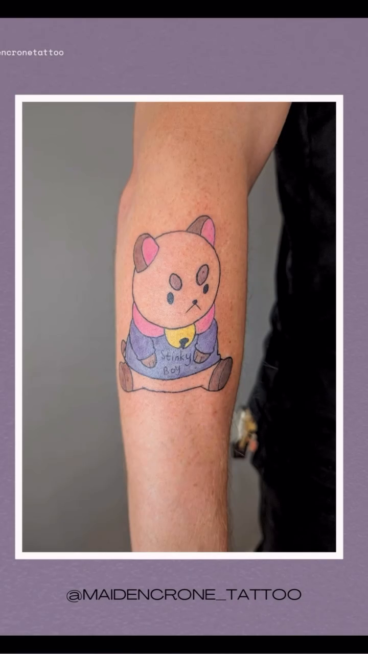 Angry cat with a bell new school tattoo on the forearm by Payton