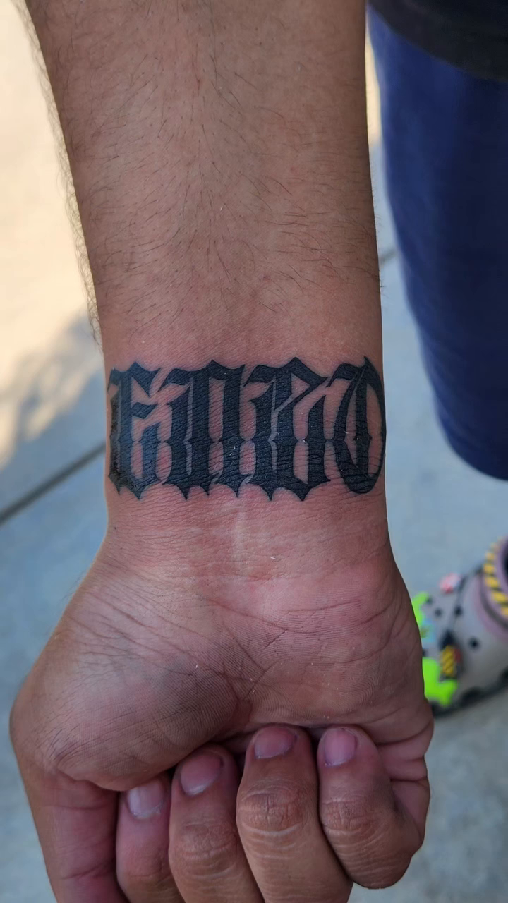 Chicano style lettering on wrist tattoo on the forearm by @youxg_guxxz