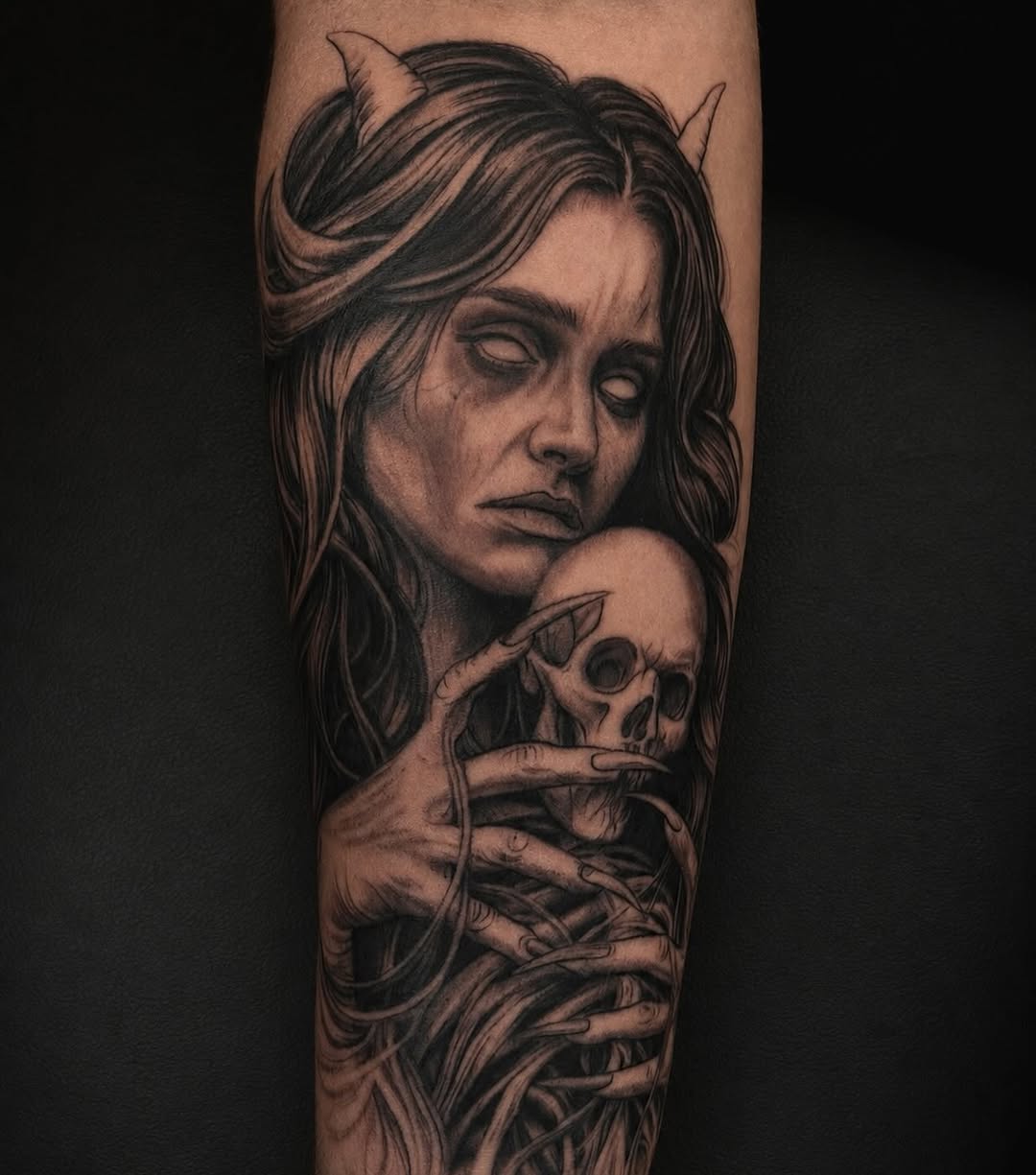 Demon woman holding a skull realism tattoo on the forearm by Jayden A