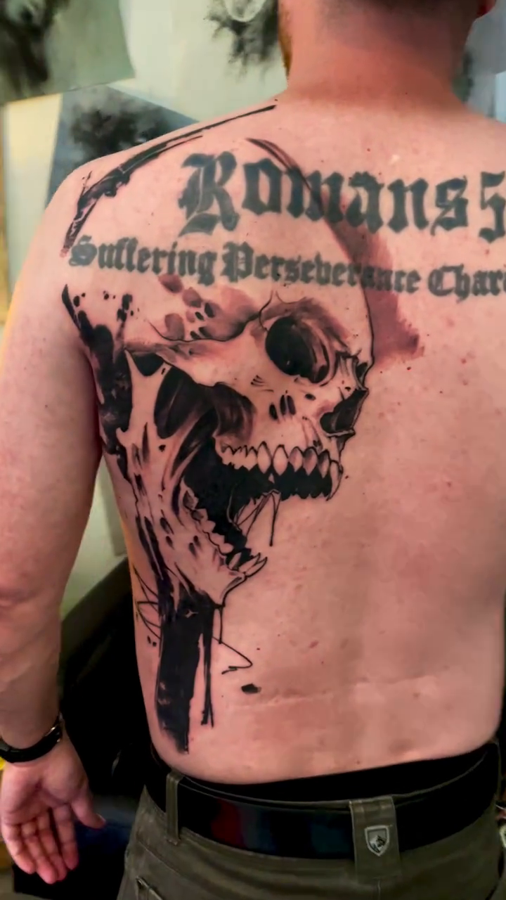 Skull with text and abstract elements realism tattoo on the back by David Garner, Los Angeles, California