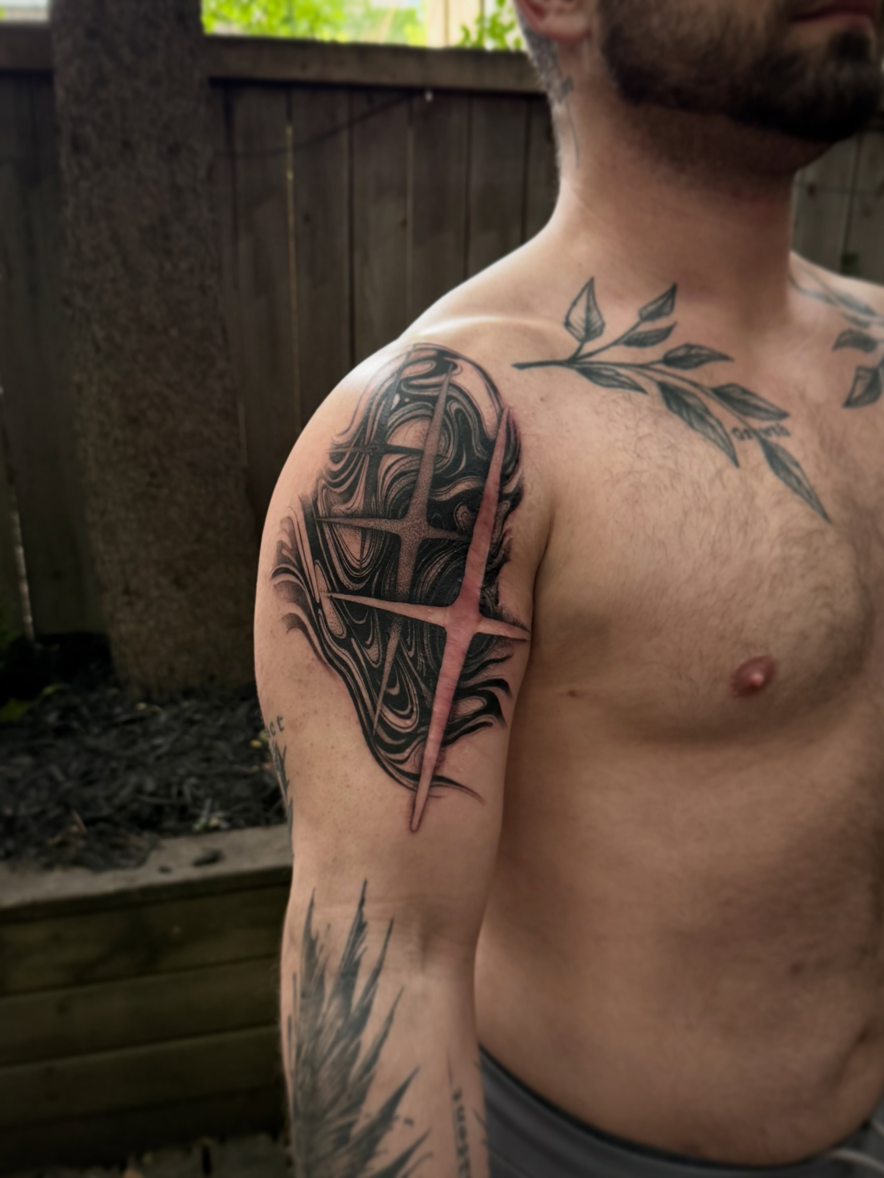Cross and abstract design black and grey tattoo on the shoulder by Vold