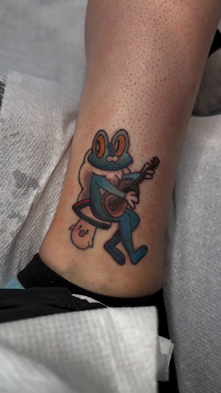 Frog playing guitar American traditional tattoo on the calf by Mercy Dean