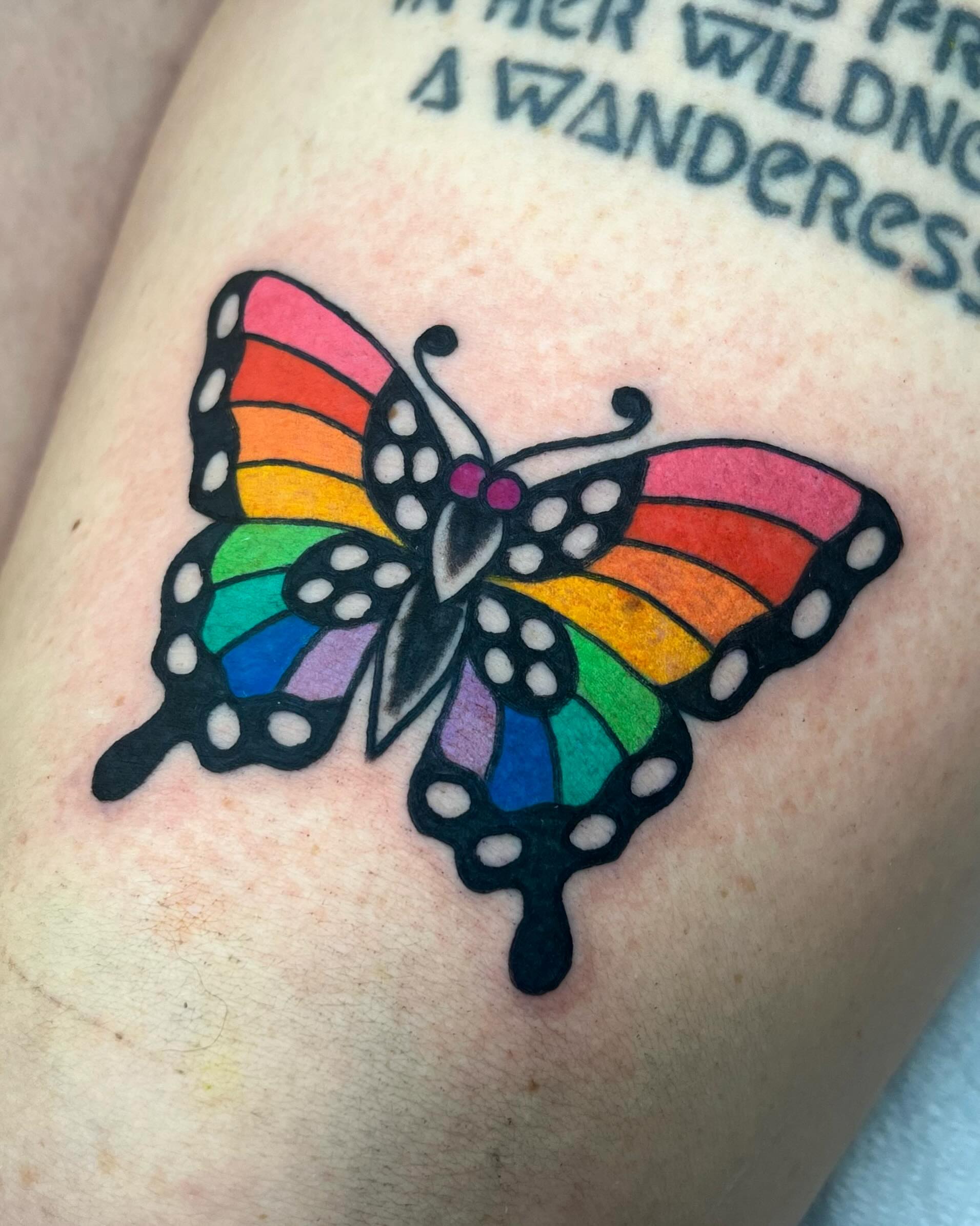 Rainbow butterfly dotwork tattoo on the forearm by Em Adkins